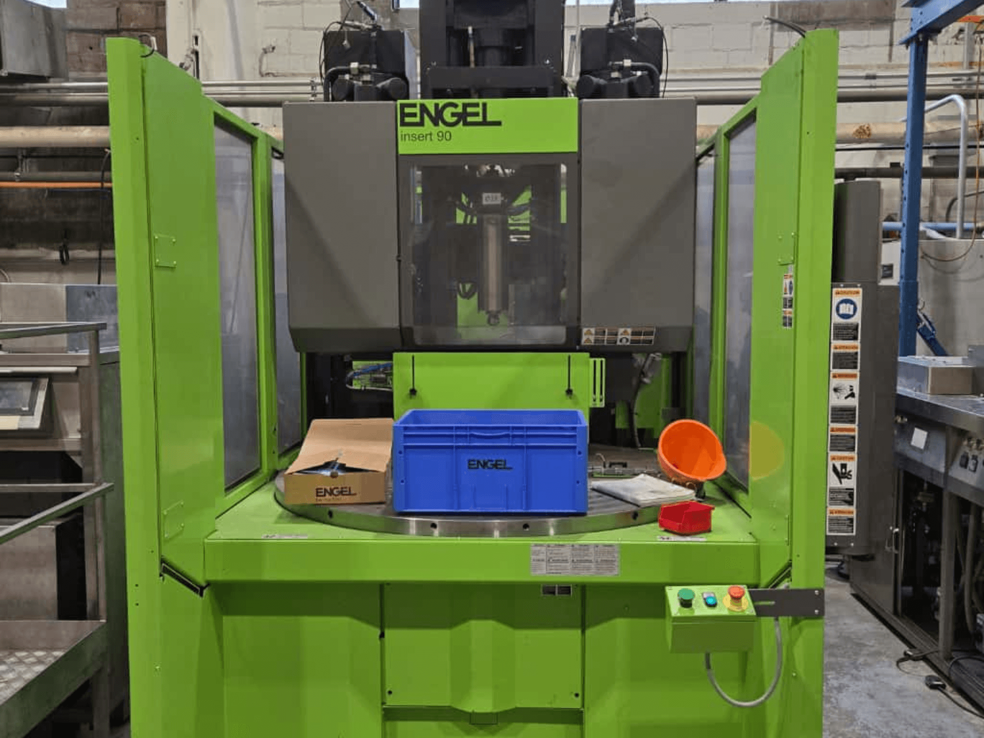 Grüne ENGEL Insert 90 Spritzgießmaschine in der Frontansicht, mit blauem Behälter und Bedienfeld mit Tasten.