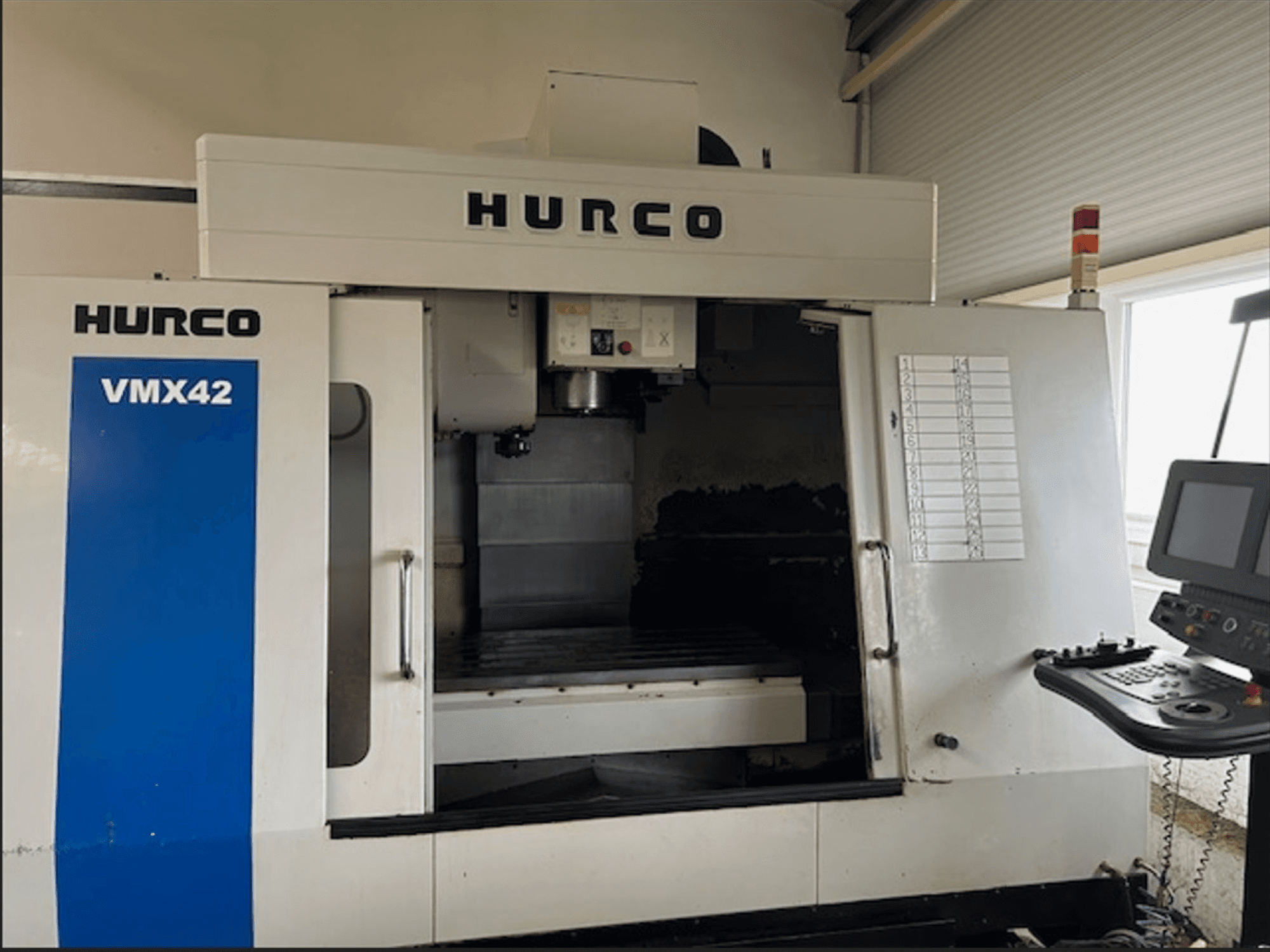 Hurco VMX42 CNC-Fräsmaschine, Vorderansicht, mit Bedienfeld und offenem Arbeitsbereich für die Bearbeitung.