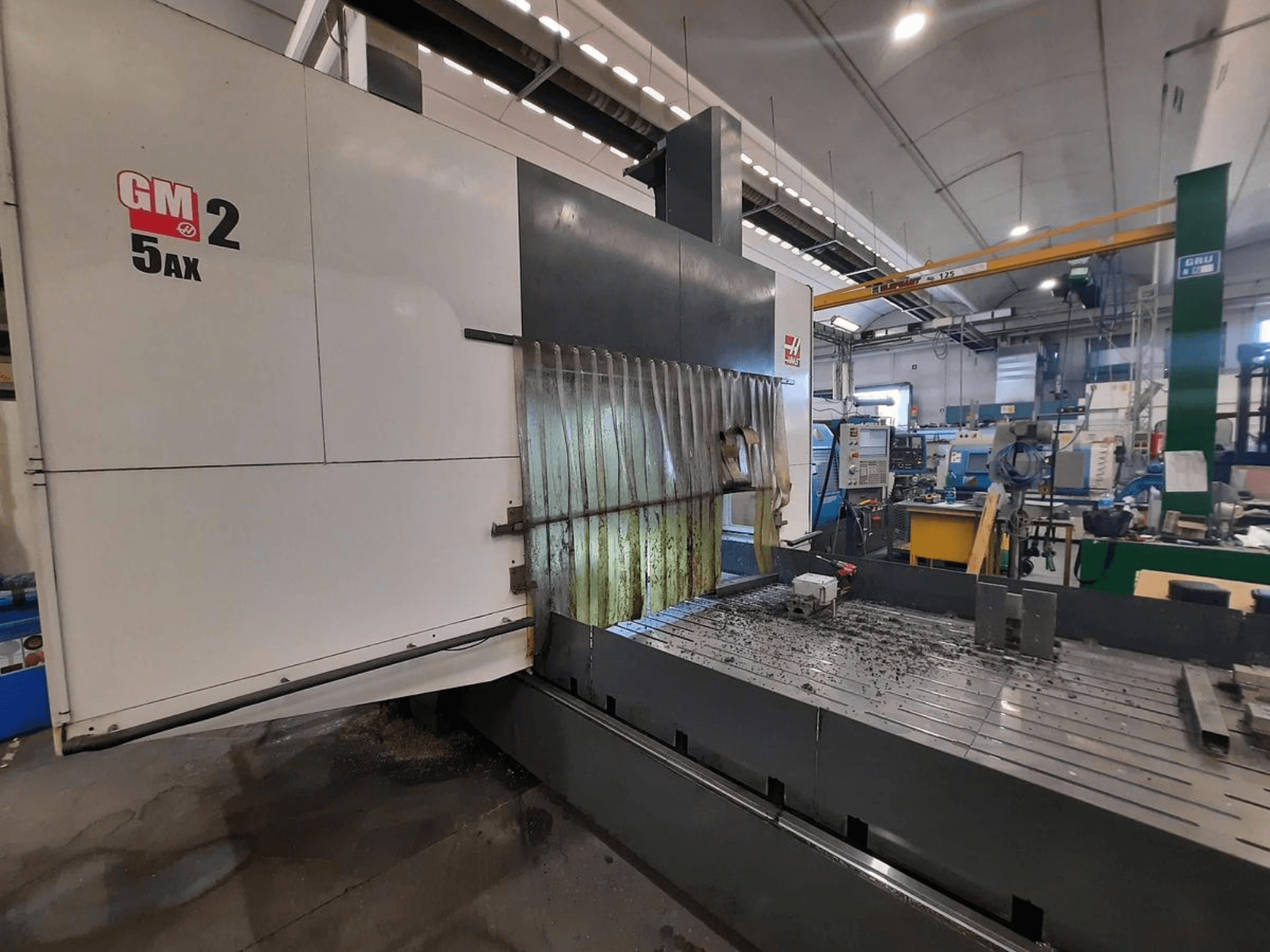 GM 2 5AX CNC-Maschine in einer Werkstatt, Seitenansicht, zeigt den Arbeitsbereich und Metallspäne auf der Bettfläche.