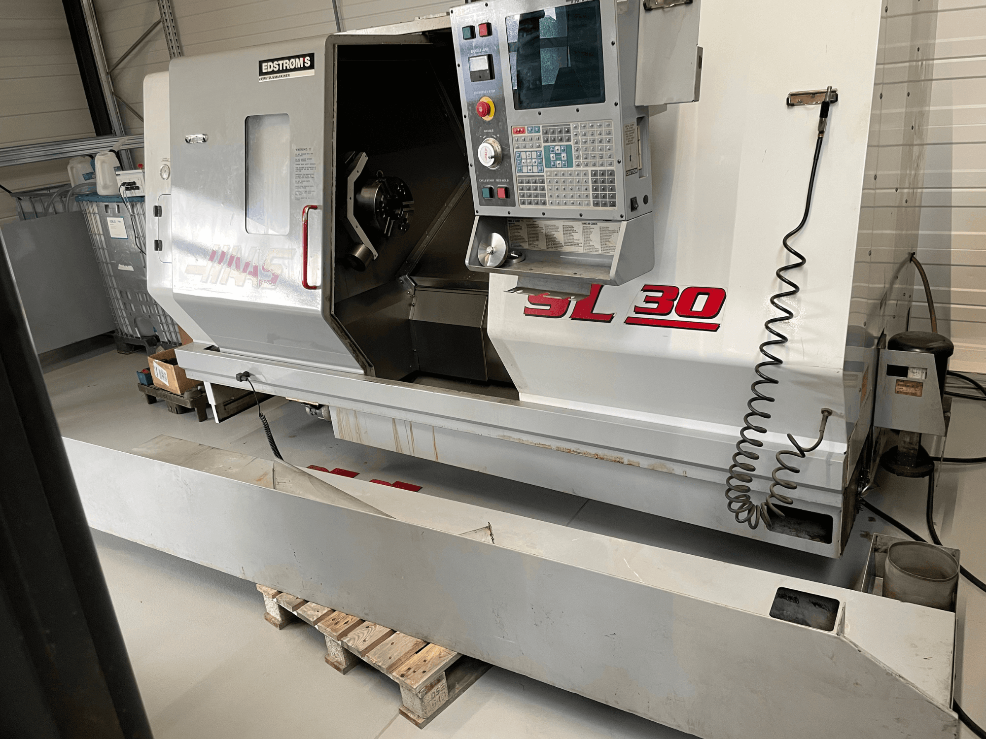 Haas SL 30 CNC-Drehmaschine in einer Werkstatt, Seitenansicht, mit Bedienfeld und offener Spindel für Bearbeitungsaufgaben.