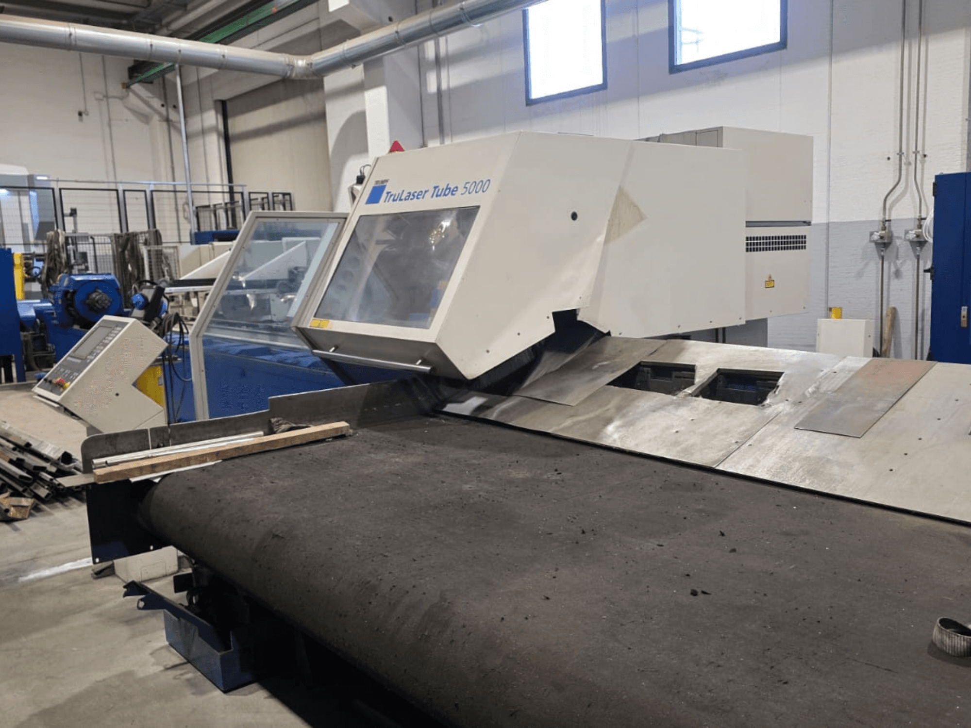 Rohrschneidemaschine TRUMPF LASERTUBE 5000, von vorne gesehen, mit Blick auf den Schneidbereich und das Bedienfeld.