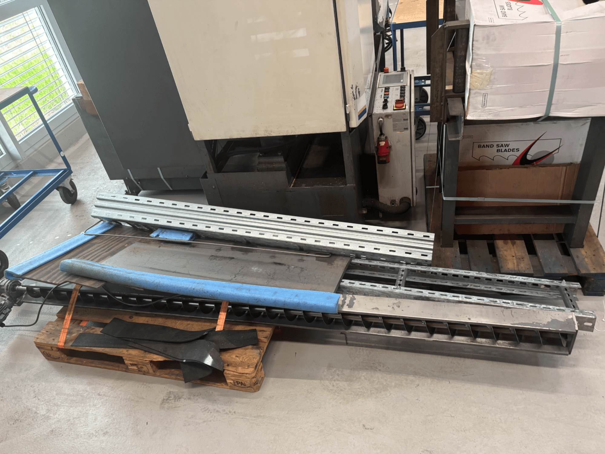 Metallbandsäge BAUER SA 430 ZA in der Seitenansicht, mit Metallrahmen und Komponenten auf einer Holzpalette.