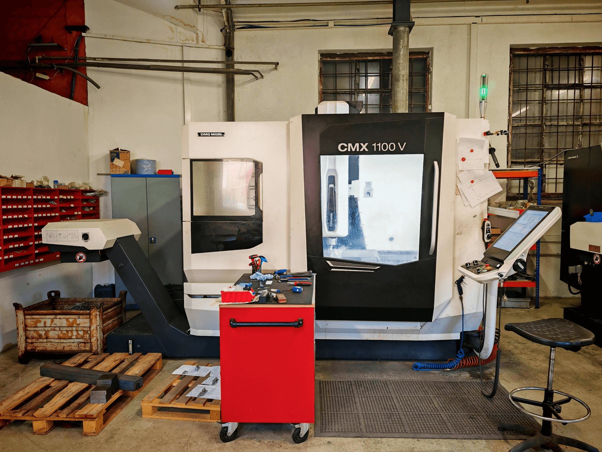 Vertikales Bearbeitungszentrum DMG MORI CMX 1100 V in der Werkstatt, Vorderansicht, mit Blick auf das Bedienfeld und die umliegenden Werkzeuge.
