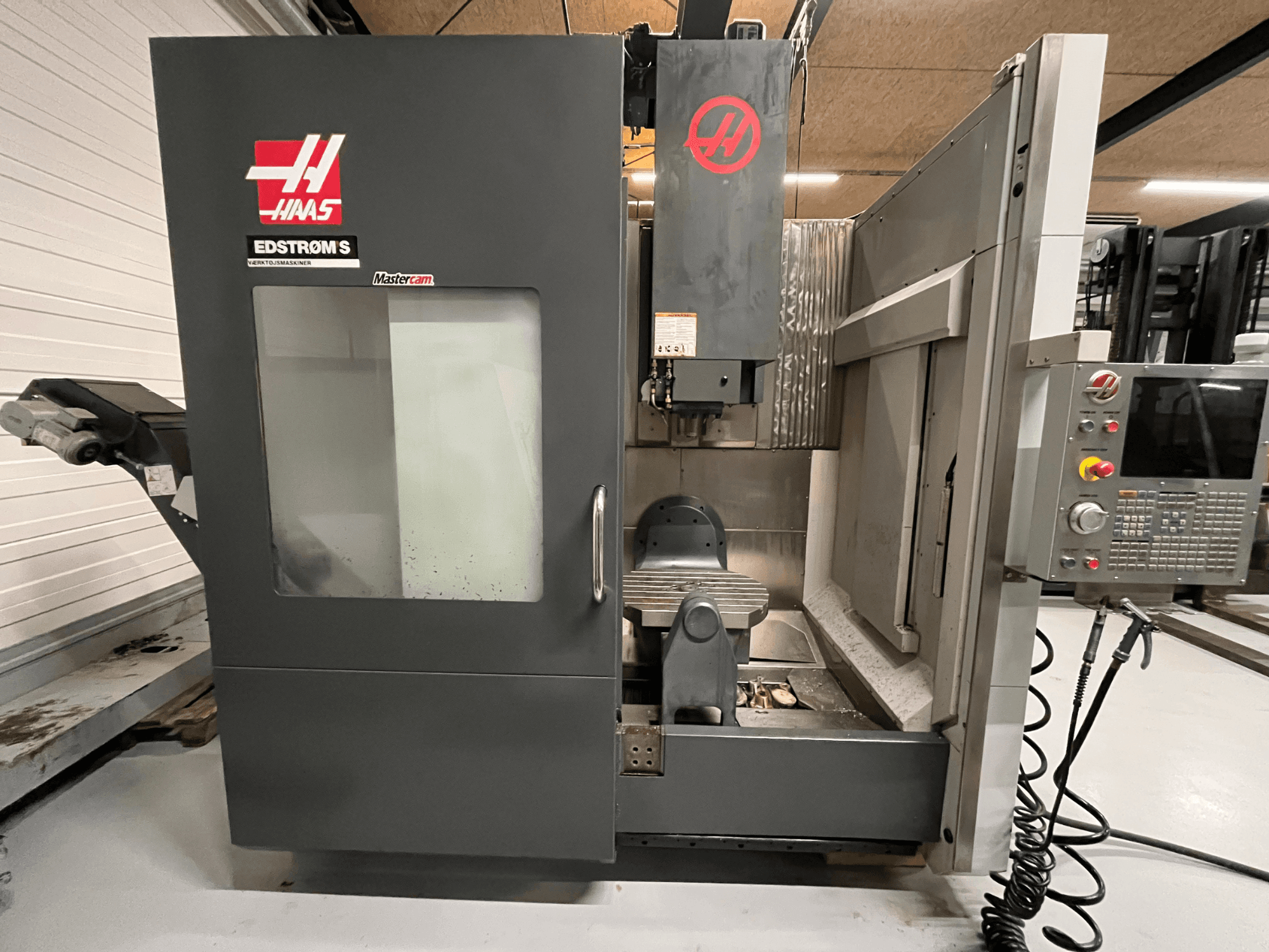 Vorderansicht der Haas EDSTROM S CNC-Maschine mit Bedienfeld, Spindelkopf und Bearbeitungstisch.