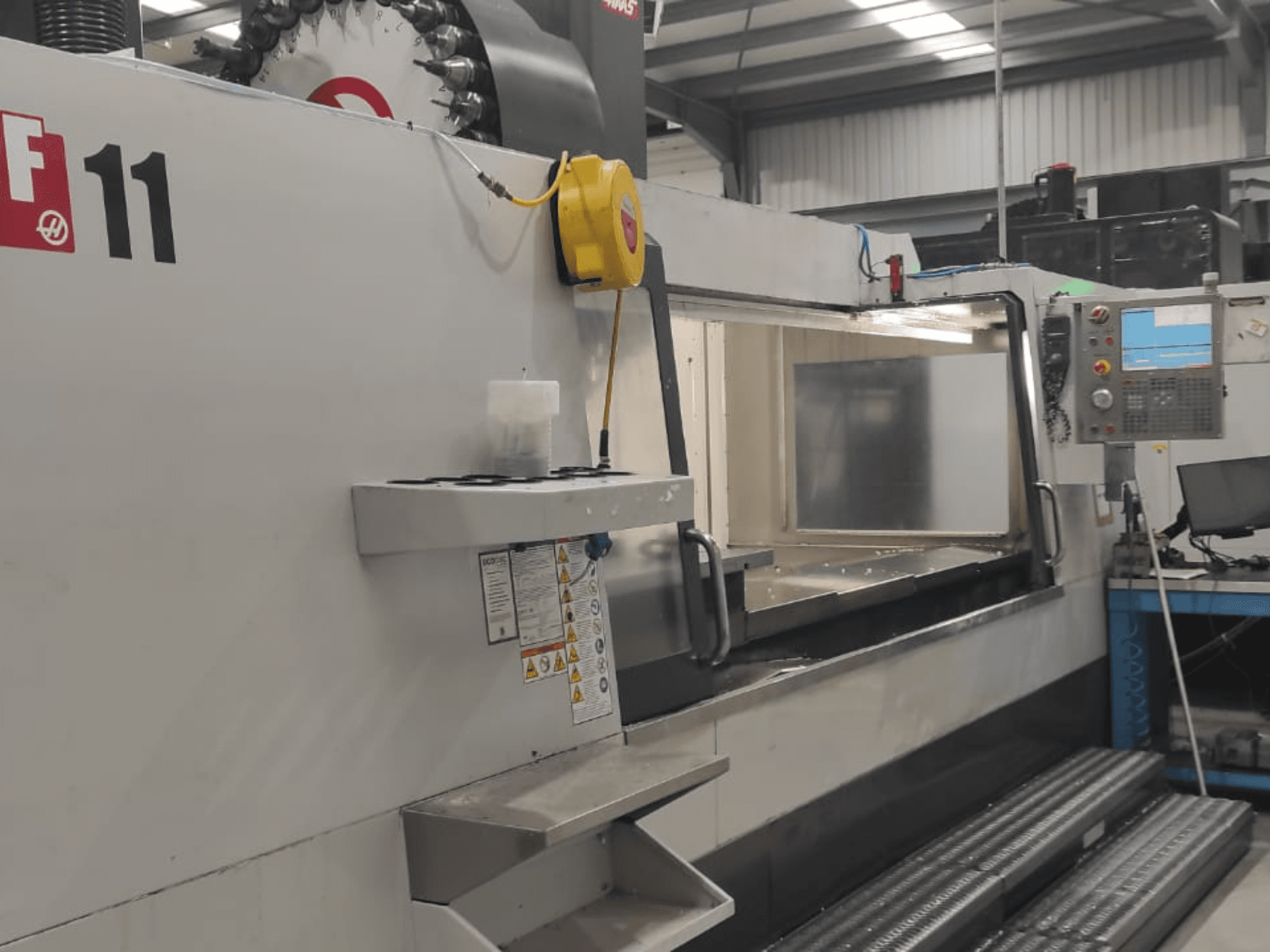 Maschinen von Haas, Modell VF-11, in der Vorderansicht mit Bedienfeld, großem Arbeitsbereich und Sicherheitsschildern.