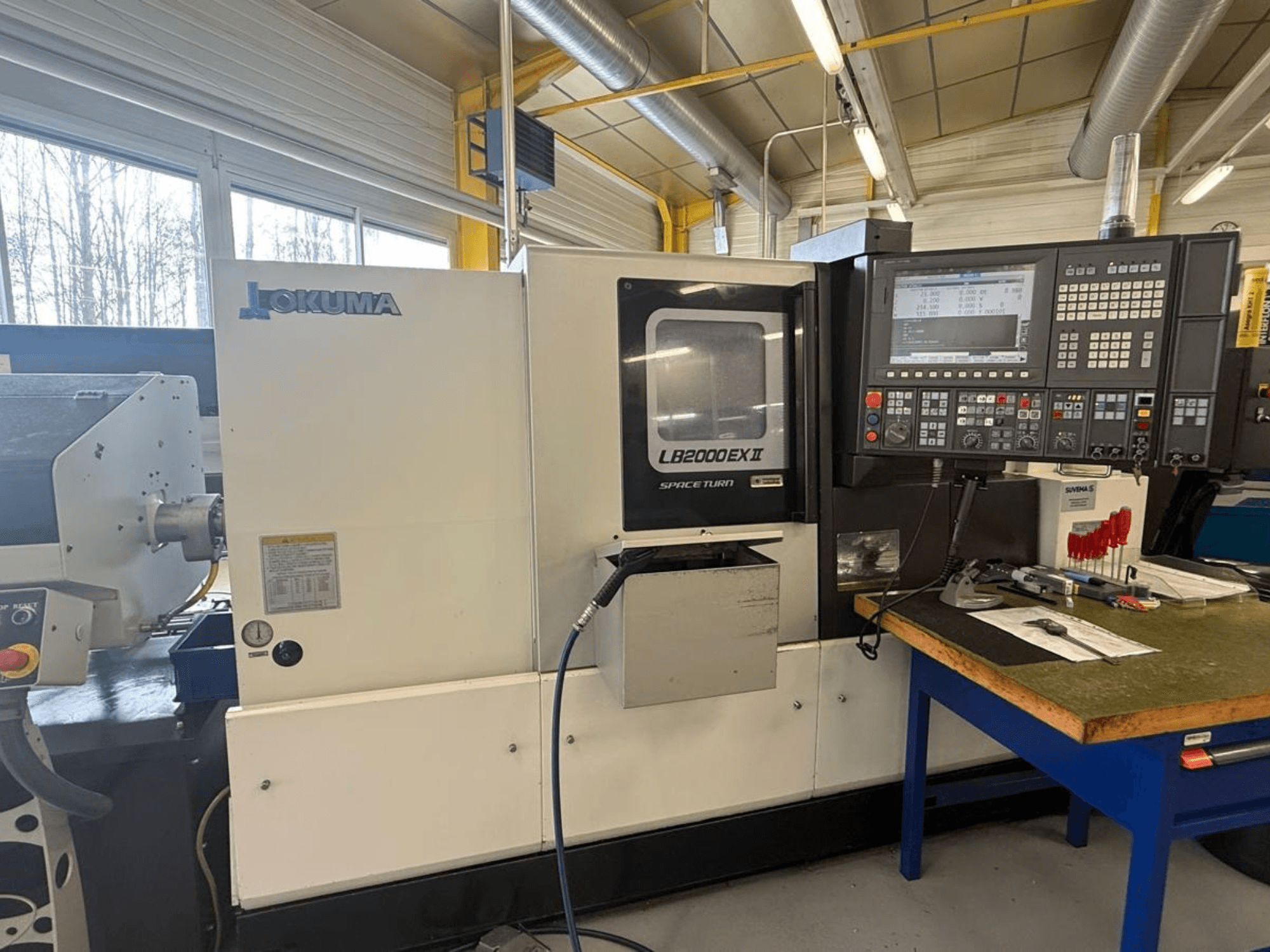 Okuma LB2000EX II Horizontal-Drehmaschine, Vorderansicht; mit Bedienfeld, Spindelbereich und umliegendem Arbeitsbereich.