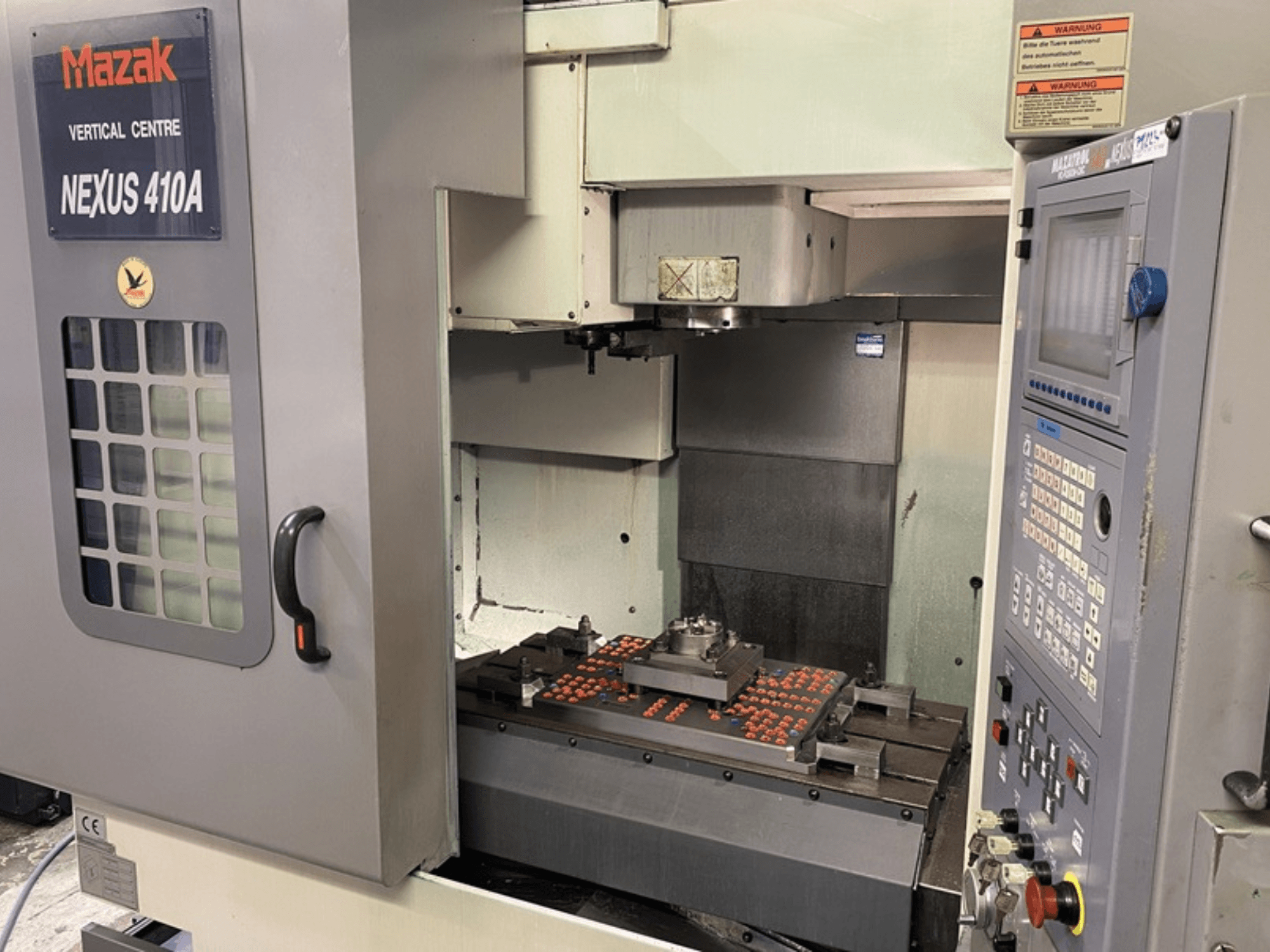 Mazak VCN410 Vertikal-Bearbeitungszentrum, Vorderansicht mit Bedienfeld und Maschineninnenraum mit montiertem Werkstück.
