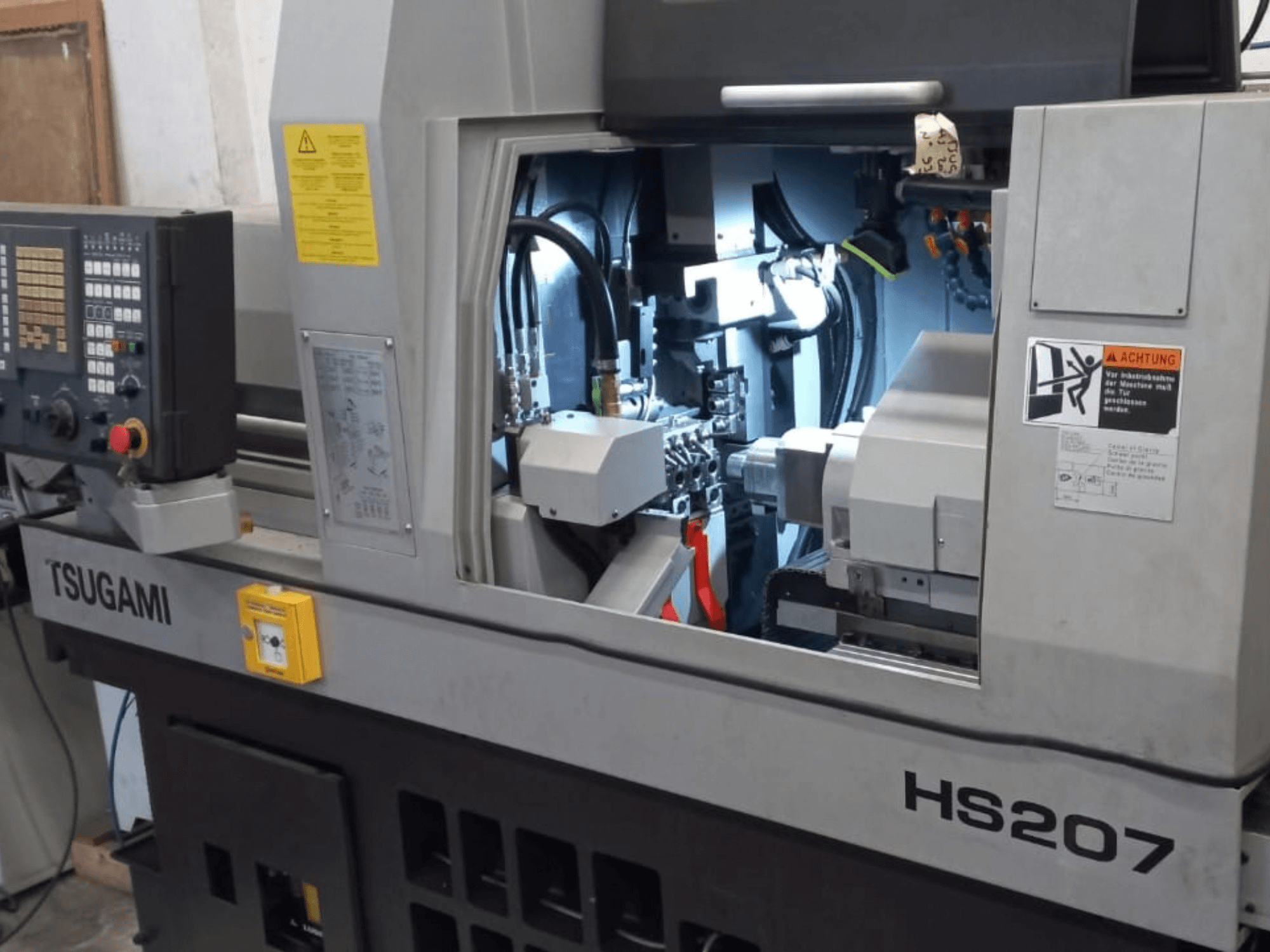 TSUGAMI HS207 Drehmaschine vom Schweizer Typ, Vorderansicht mit Bedienfeld und internen Komponenten.
