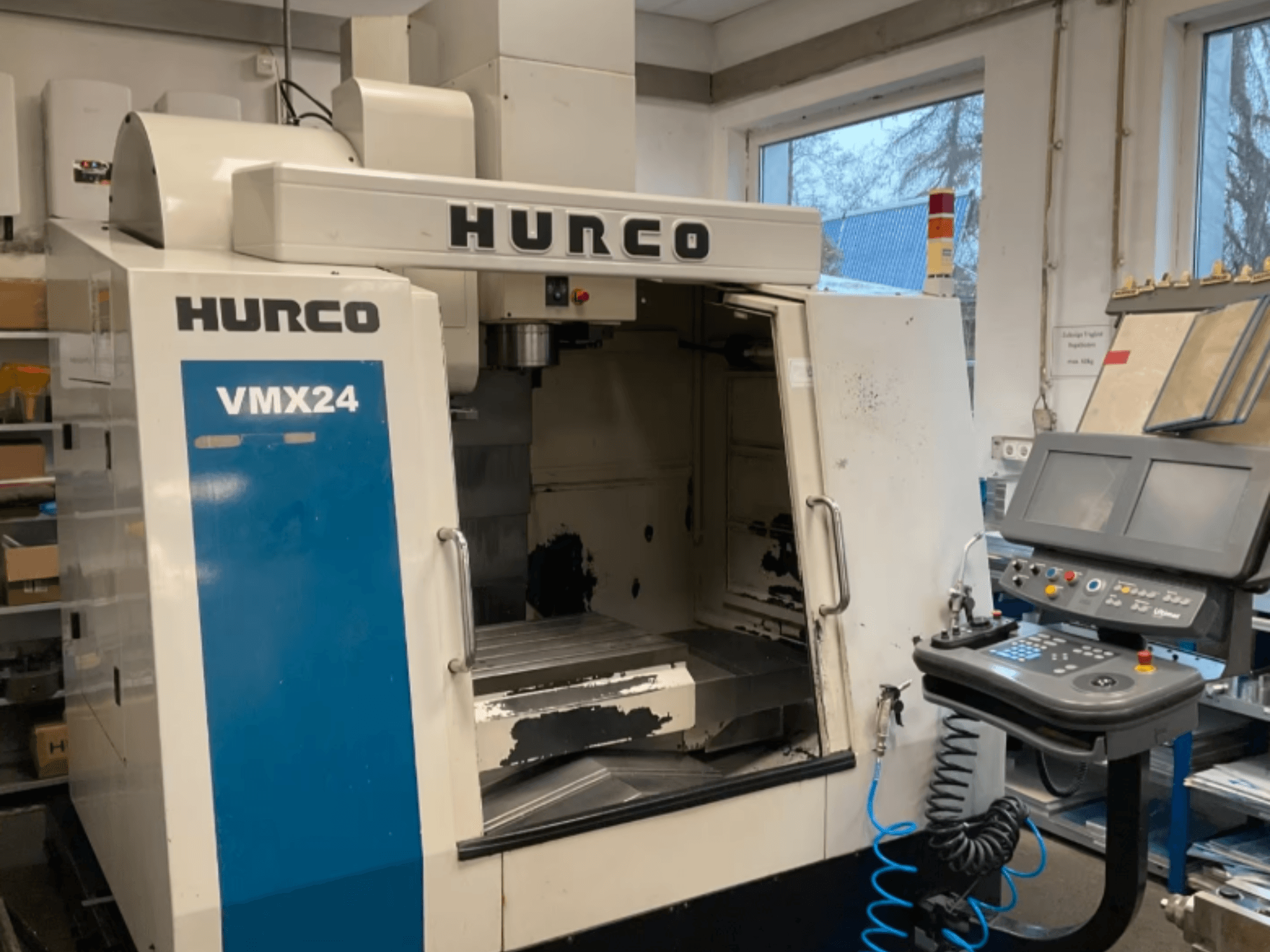 Das vertikale Bearbeitungszentrum Hurco VMX24 in der Vorderansicht, mit Blick auf das Bedienfeld, den Spindelkopf und den Arbeitsbereich; leichte Gebrauchsspuren sind zu erkennen.