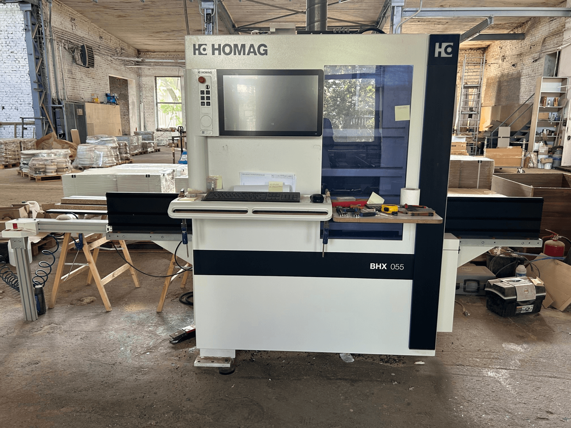 HOMAG WEEKE OPTIMAT BHX 055 CNC-Bearbeitungszentrum, Vorderansicht, mit Bedienfeld und Arbeitsbereich mit Werkzeugen.