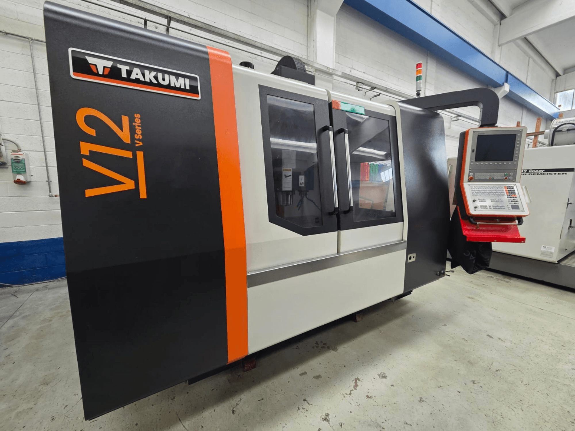 CNC-Fräsmaschine Takumi V12 V-Serie, Vorderansicht, mit Bedienfeld und großen Glasfenstern.