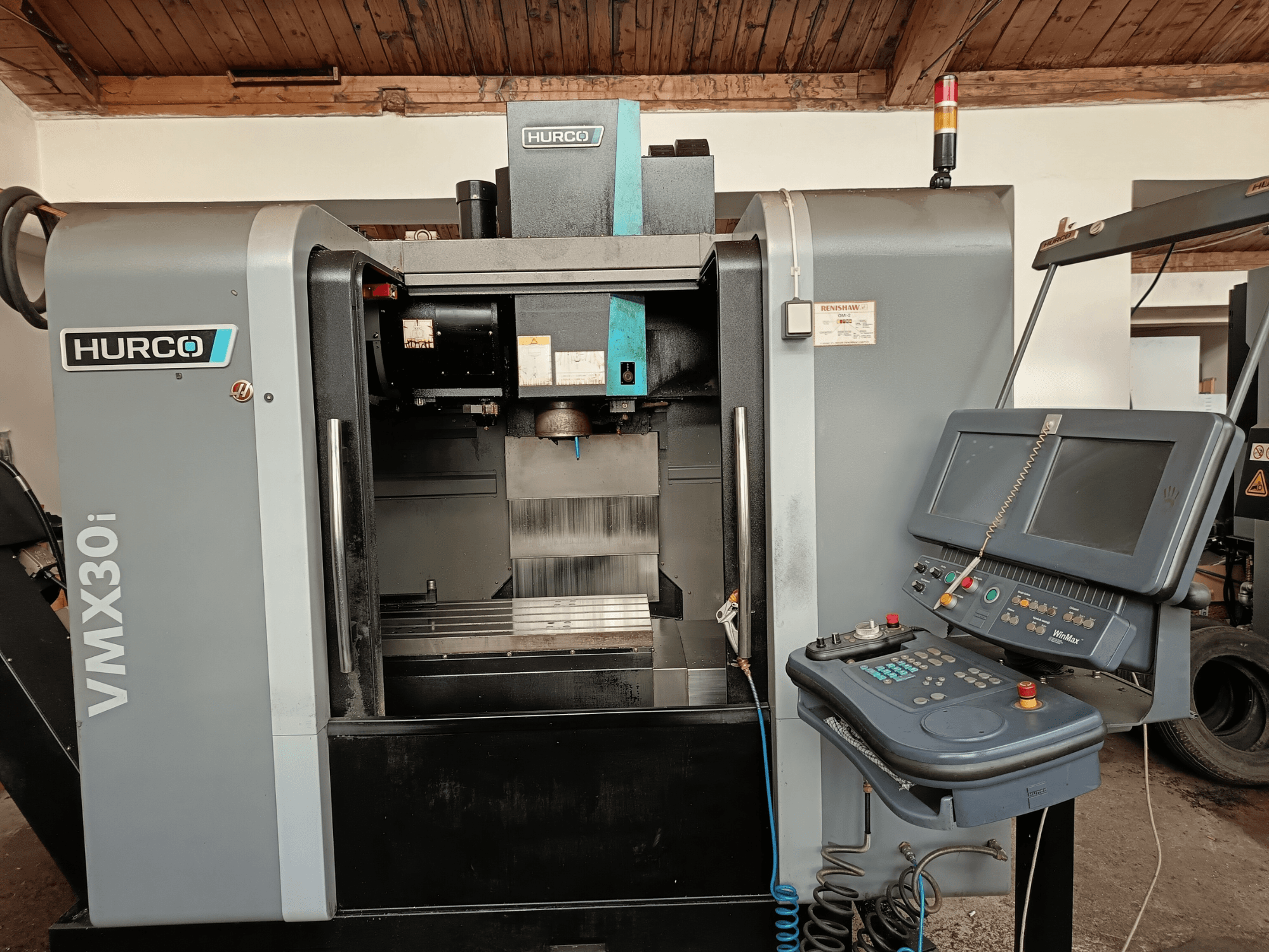 HURCO VMX30i Bearbeitungszentrum in der Vorderansicht, mit Bedienfeld mit Tasten und Monitor, metallischem Arbeitsbereich und Warnleuchte.