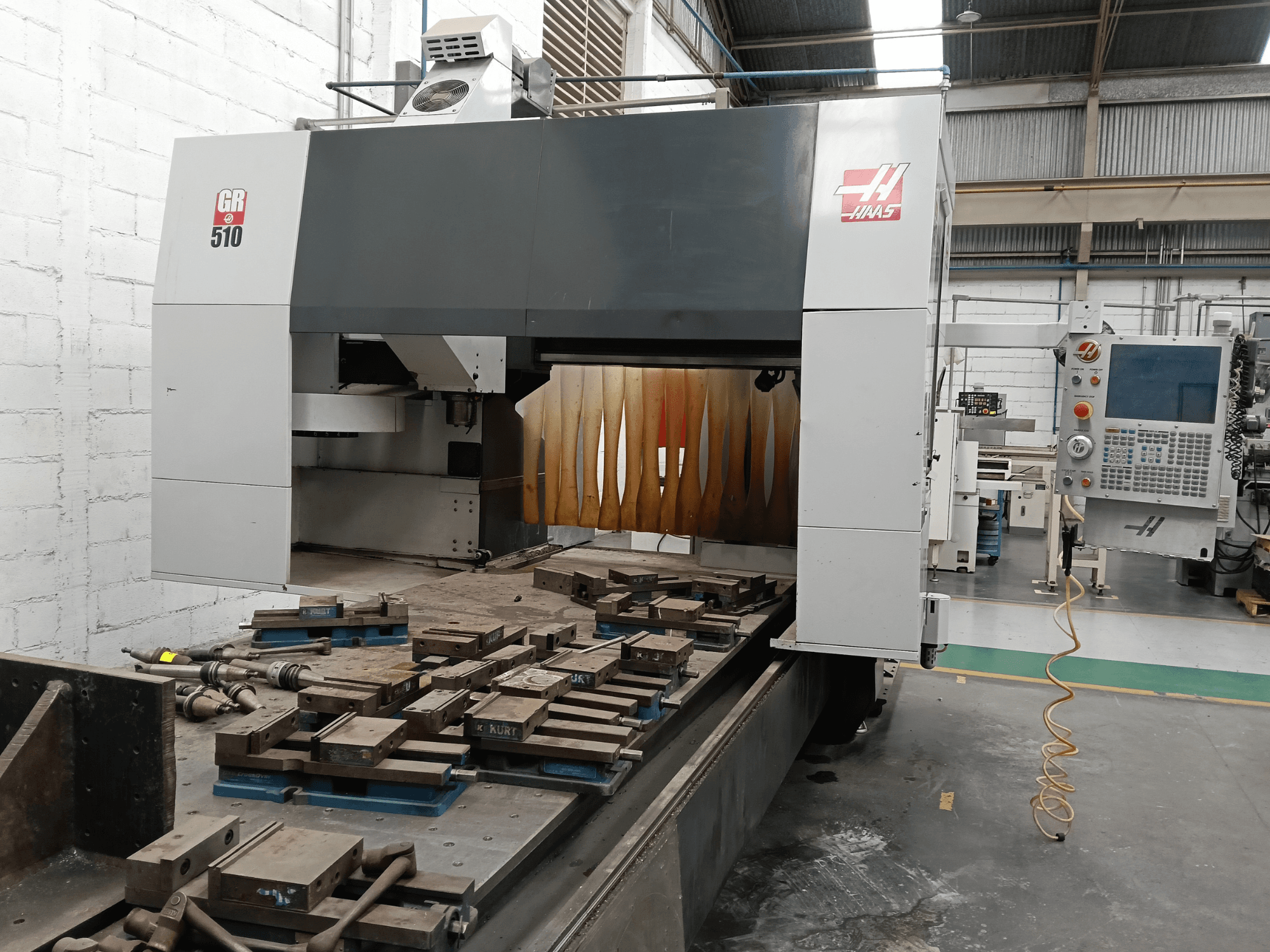 Vorderansicht der HAAS GR-510 Portalfräsmaschine mit Blick auf das Bedienfeld und die bearbeiteten Werkstücke auf dem Tisch.