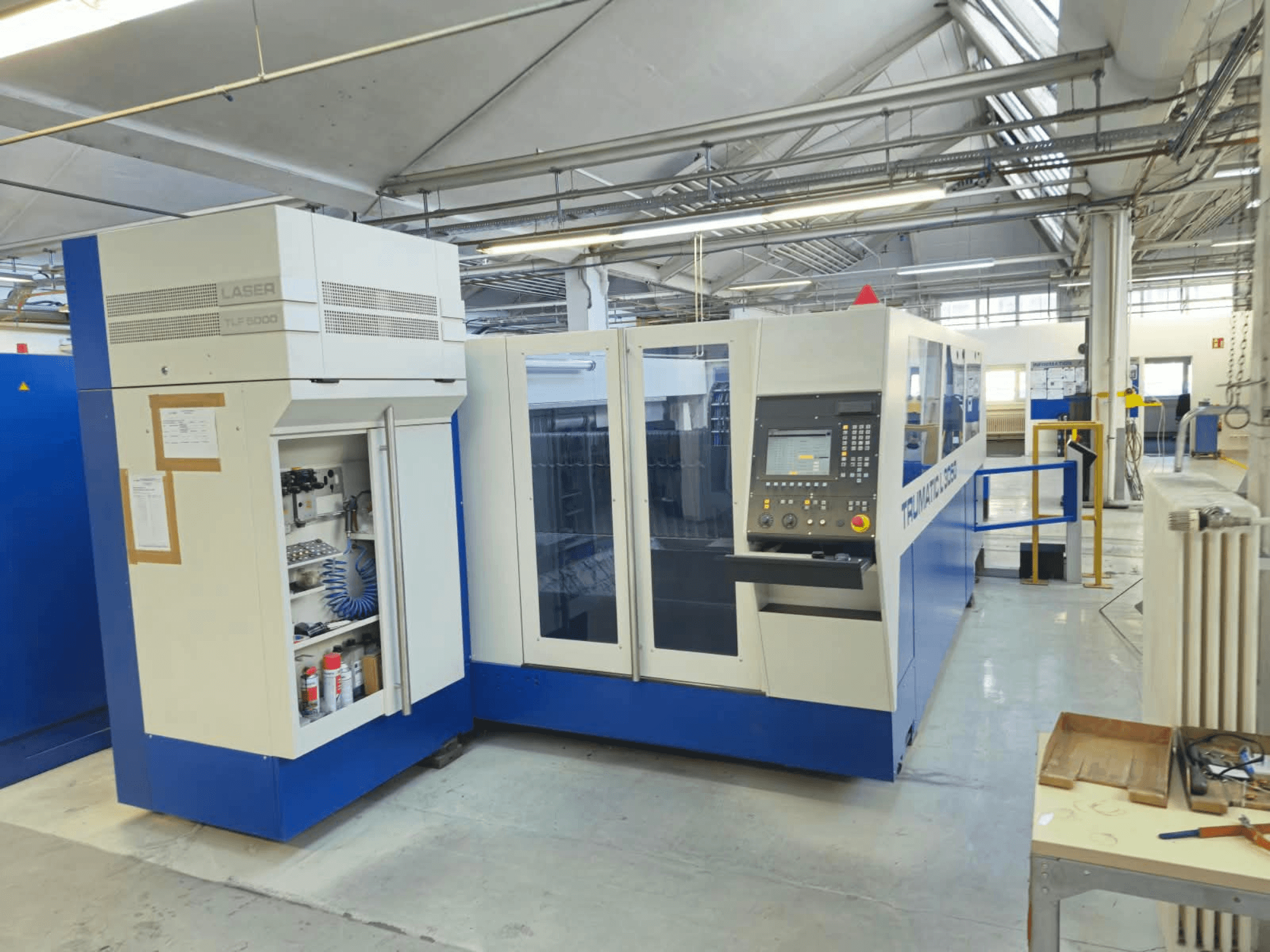 TRUMPF TruLaser L3050 CO₂-Laserschneidanlage, Vorderansicht, mit Bedienfeld und Wartungsklappe, in Werksausstattung.