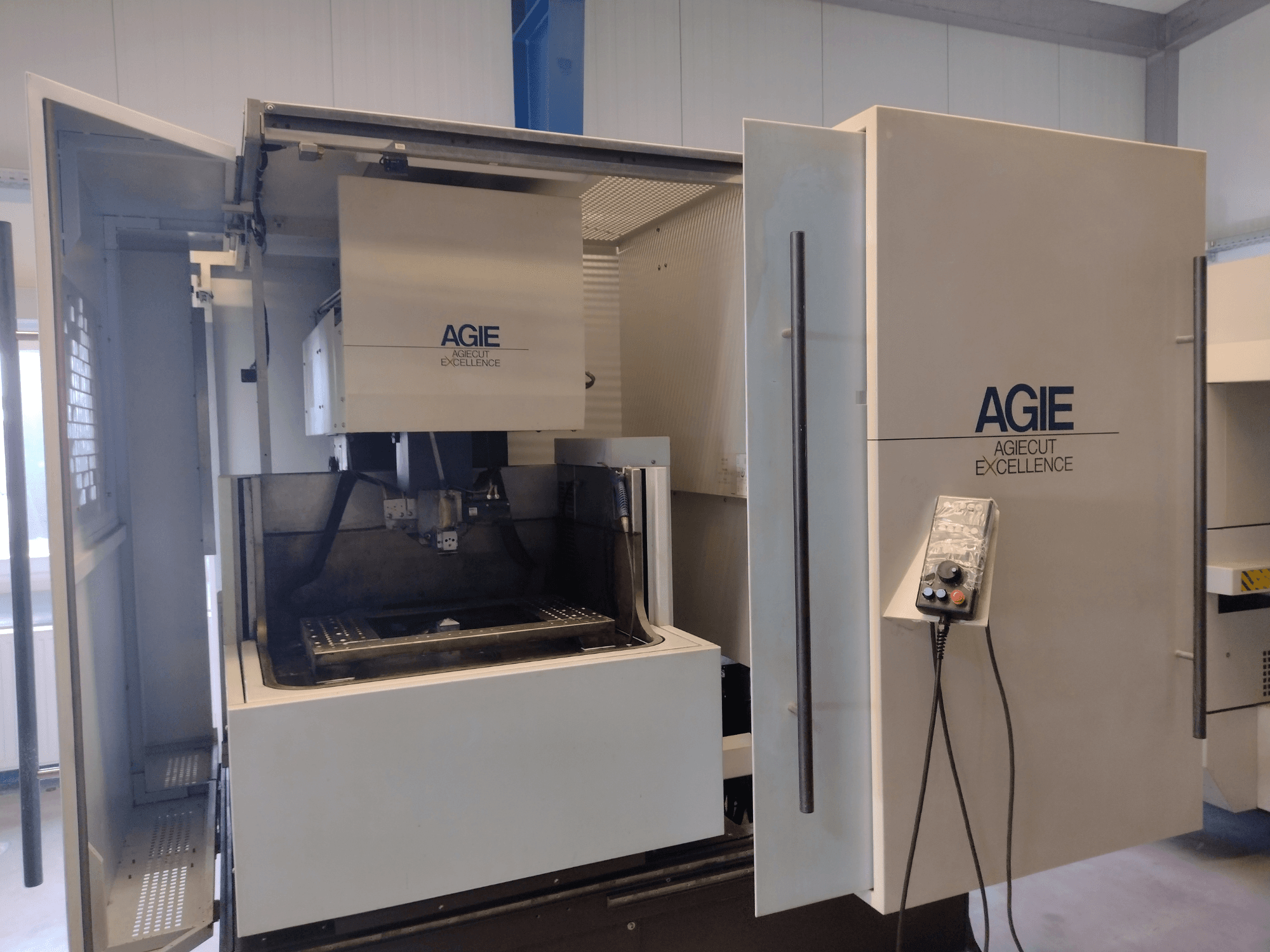 AGIE Progress 3-Draht-Funkenerosionsmaschine in Vorderansicht, mit offenem Gehäuse, Bedienfeld und Bearbeitungsbereich.