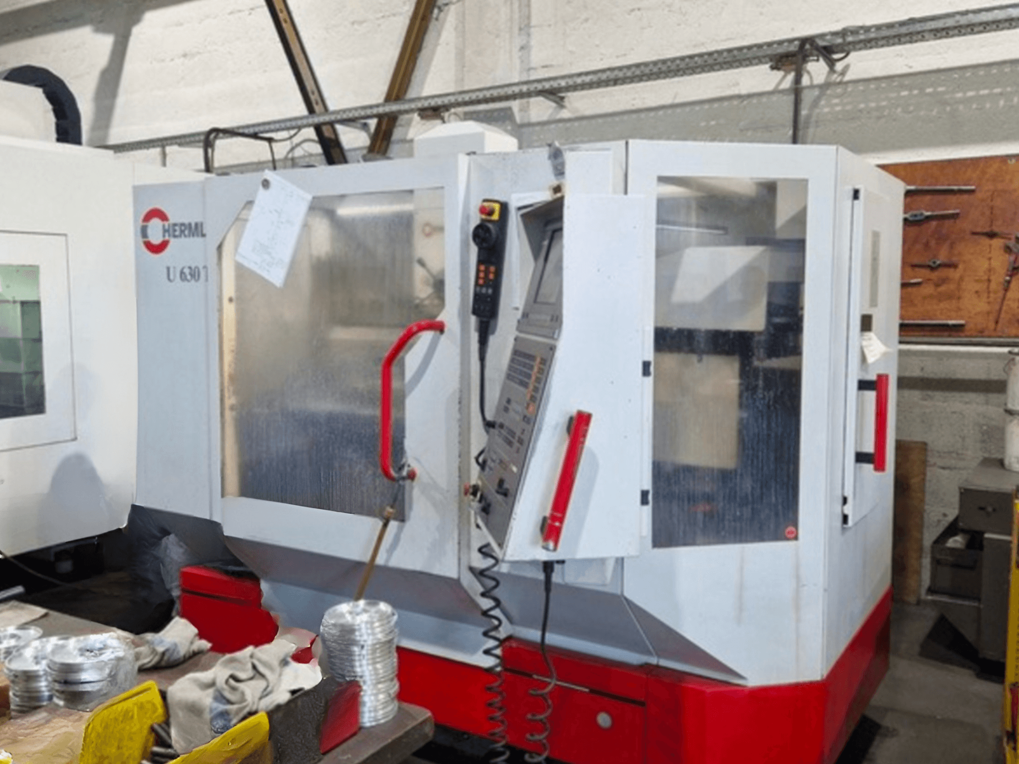 HERMLE Universal-Bearbeitungszentrum U 630 T in der Frontansicht mit geöffneter Tür und Bedienfeld mit sichtbaren Tasten und Werkzeugen.