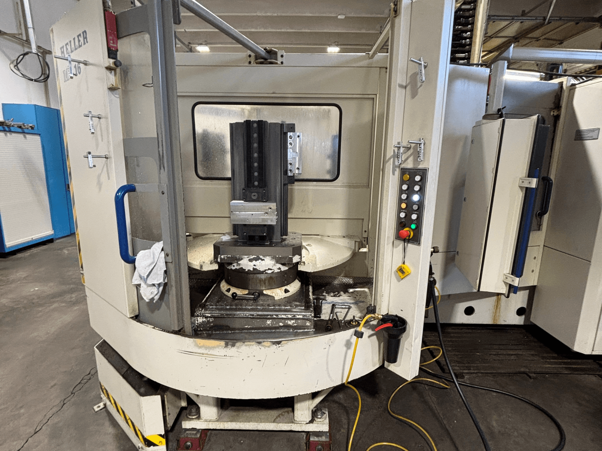 Heller Bearbeitungszentrum, Modell vertikal, Vorderansicht mit Spindel, Bedienfeld und Arbeitstisch mit angebauter Ausrüstung.