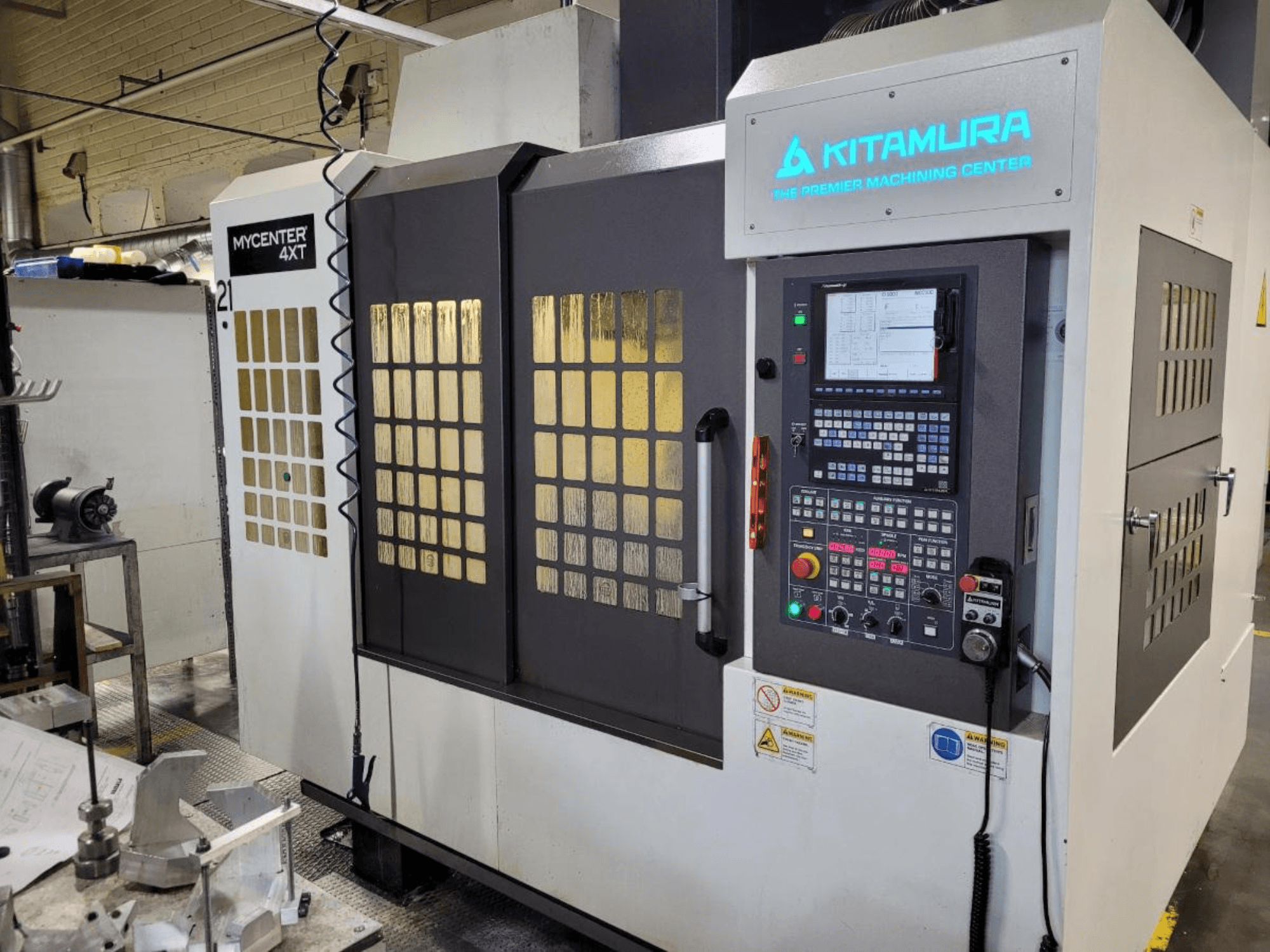 Vertikale Ansicht eines Kitamura Mycenter-4XT-Bearbeitungszentrums mit Bedienfeld und beleuchtetem Branding.