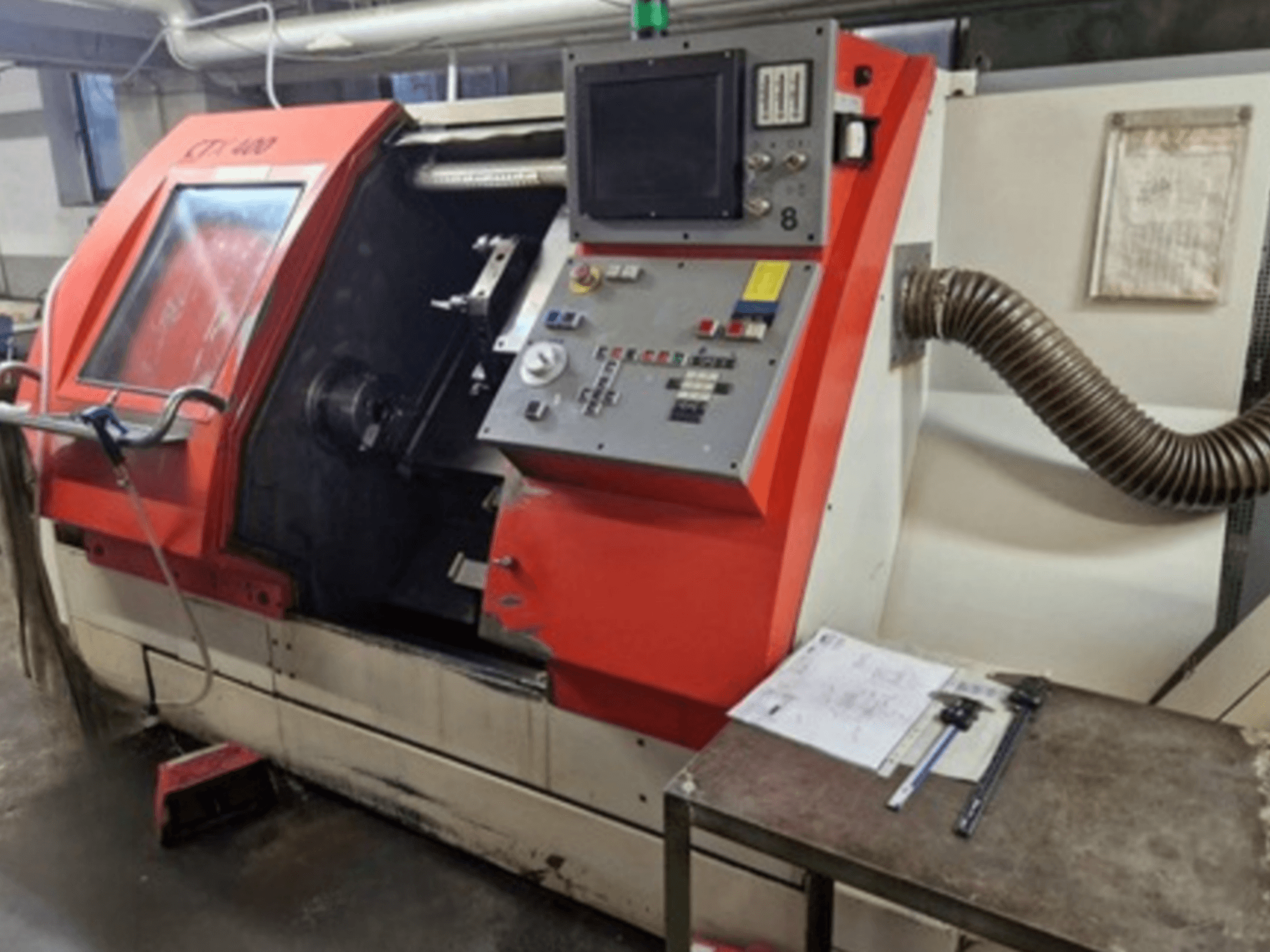 Gildemeister CTX 400 Horizontaldrehmaschine in der Vorderansicht mit Bedienfeld, geöffneter Tür und Werkstatttisch mit Werkzeugen.