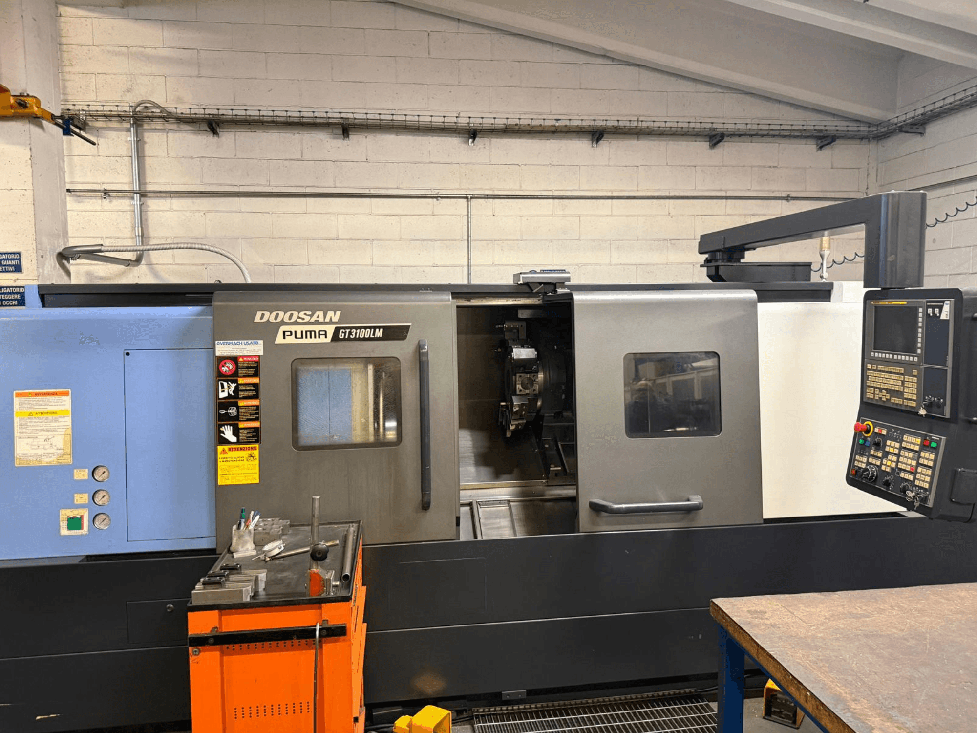 Vorderansicht der horizontalen Drehmaschine DOOSAN PUMA GT3100LM mit Bedienfeld und Arbeitsbereich mit Werkzeugen.