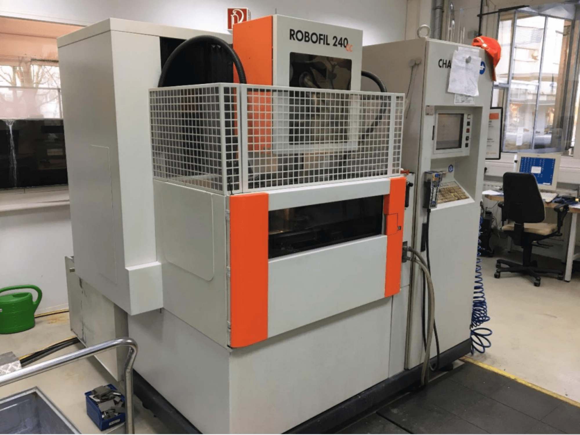 Vorderansicht einer CHARMILLES ROBOFIL 240 CC-Drahterodiermaschine mit Schutzgitter und Bedienfeld in einer Werkstatt.