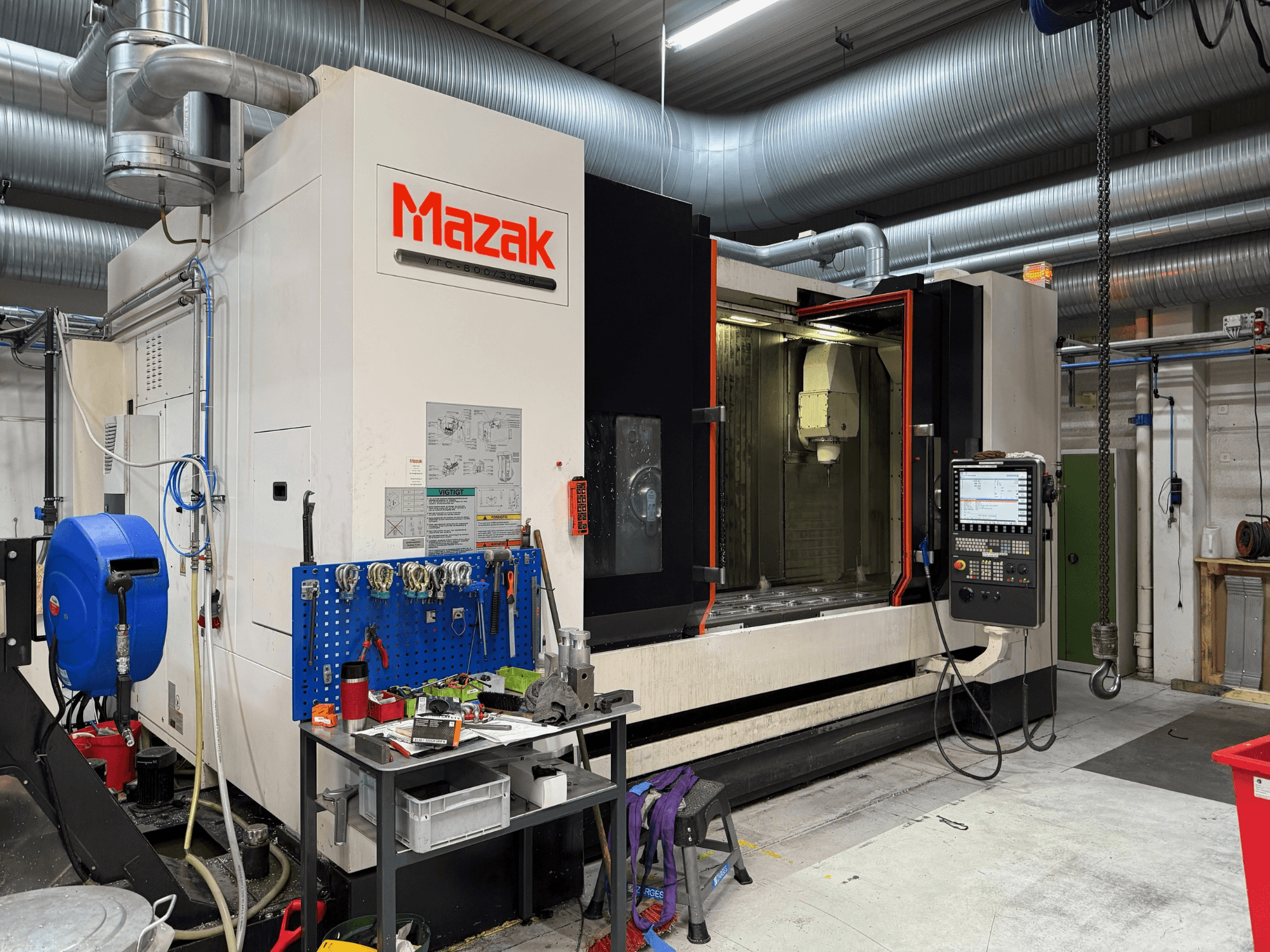Mazak CNC-Maschine in der Frontalansicht, mit Bedienelementen, Werkzeugen und Arbeitsbereich in einer Bearbeitungsumgebung.