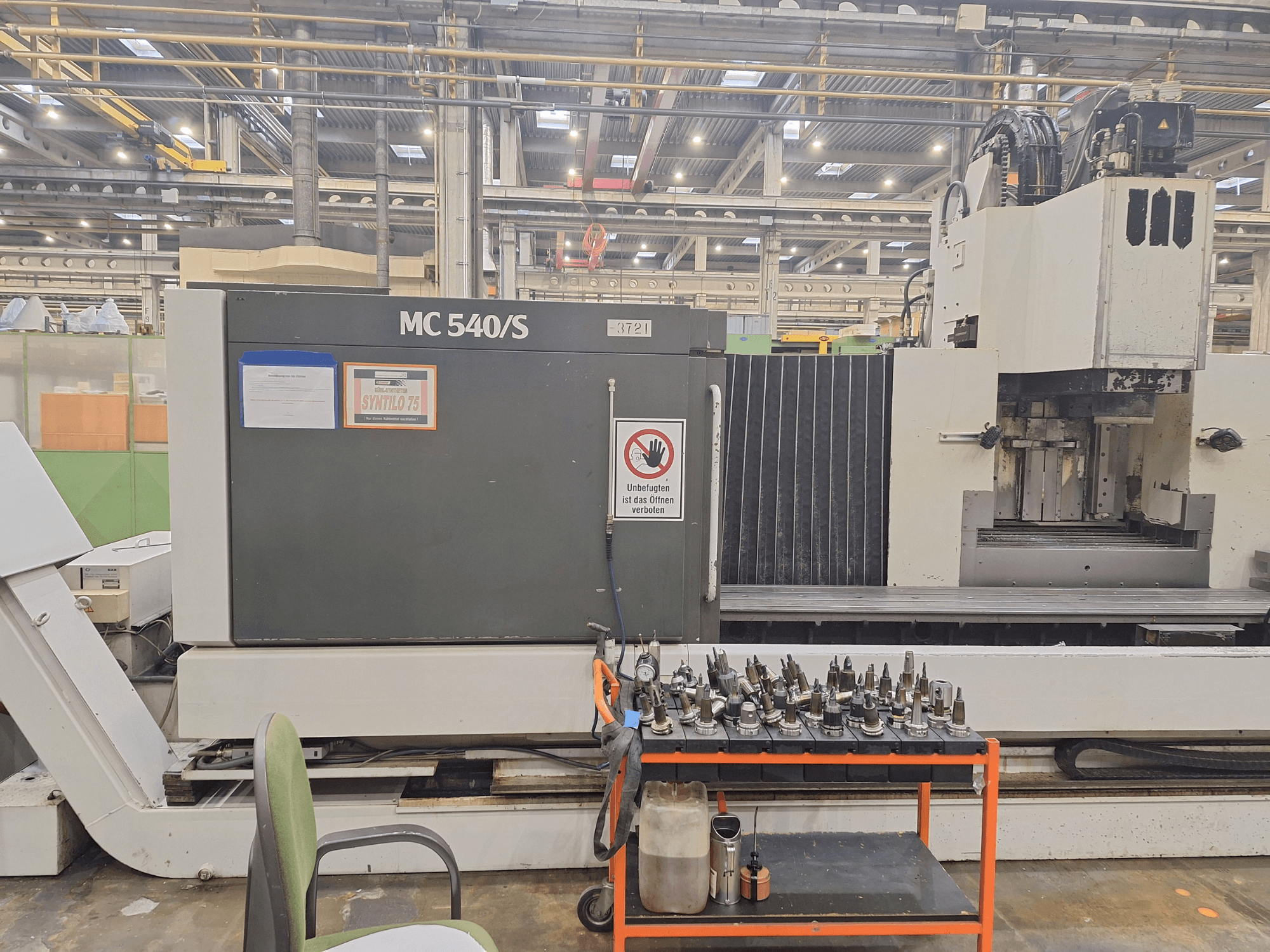 Vertikales Bearbeitungszentrum STAMA MC 540S in einer Werkstatt, Seitenansicht mit Werkzeughaltern auf einem Wagen daneben.