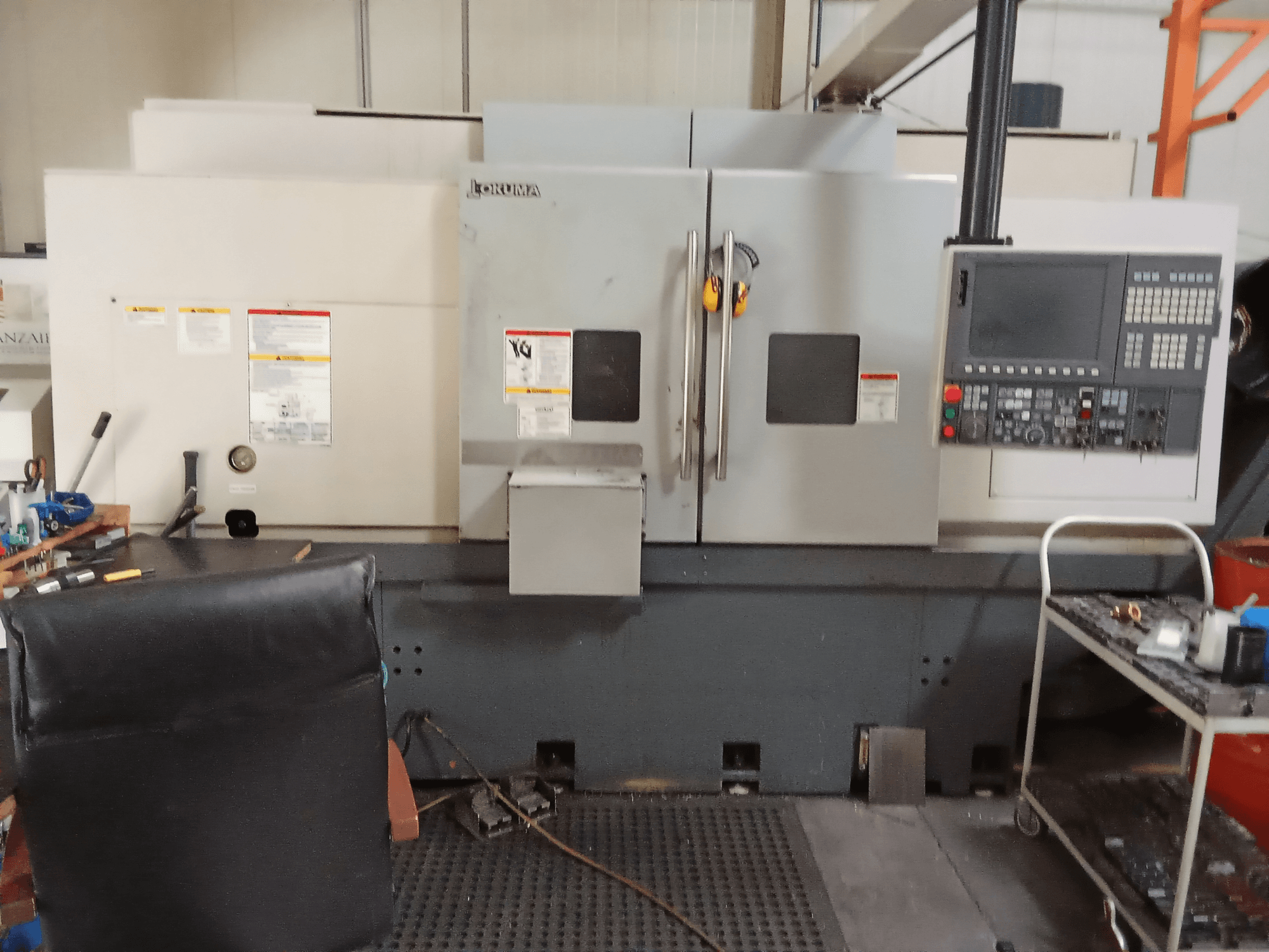 Okuma Genos L300 E-M Horizontaldrehmaschine in der Vorderansicht mit Bedienfeld und Doppeltüren in einer Werkstattumgebung.