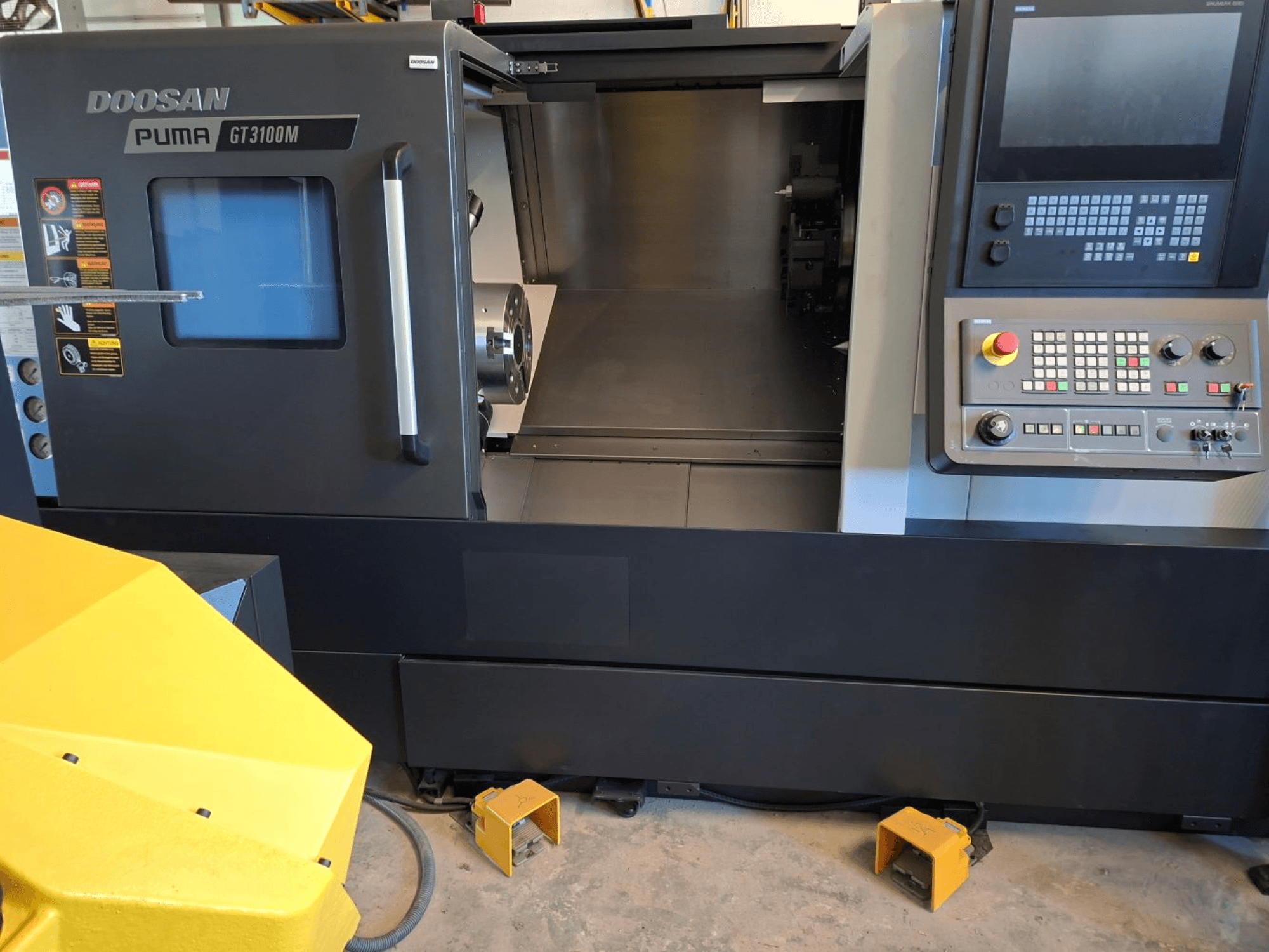 DOOSAN Puma GT 3100 M Horizontal-Drehmaschine in der Vorderansicht, mit Bedienfeld, offenem Revolver und Innenraum.