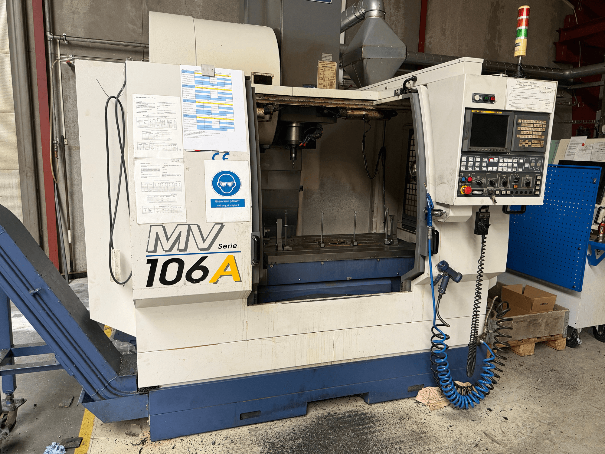 Vertikales Bearbeitungszentrum YCM MV106A, Vorderansicht mit Bedienfeld und Arbeitsbereich, inklusive technischer Dokumentation.