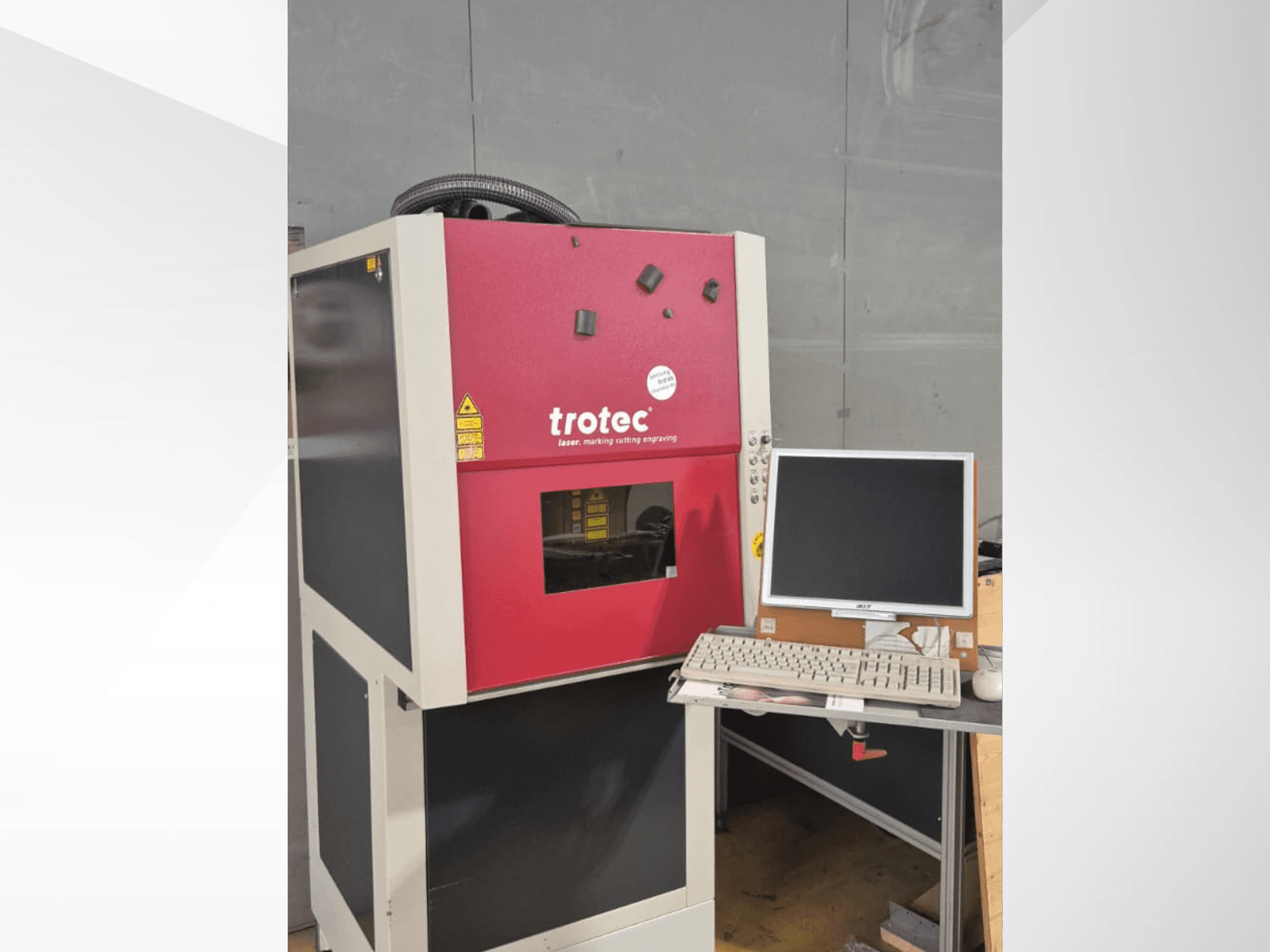 Rote Trotec-Laser-Work-Station von vorne gesehen, mit Monitor und Tastatur auf einem Arbeitstisch.