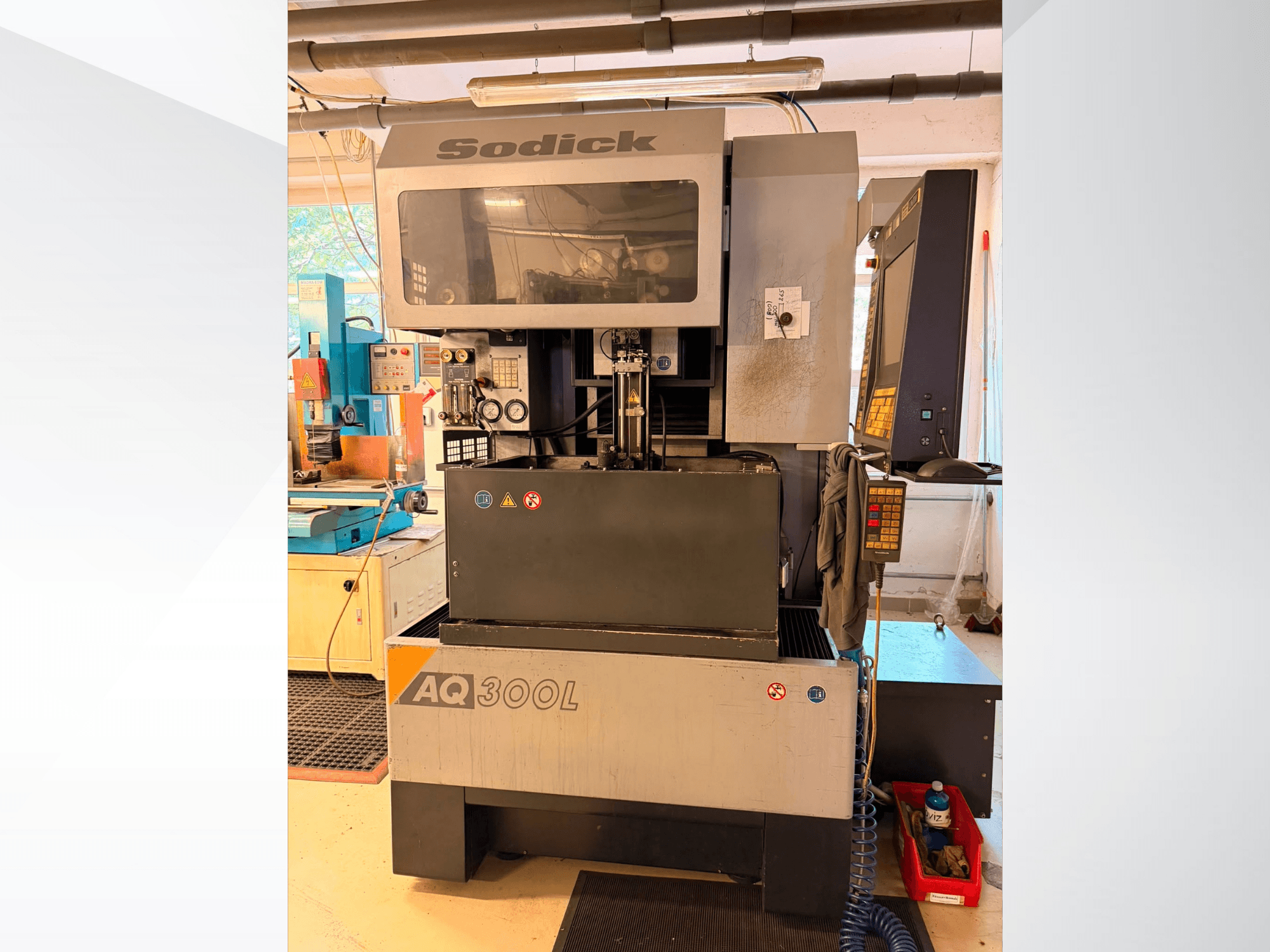 Sodick AQ300L Drahterodiermaschine, Vorderansicht, mit sichtbarem Bedienfeld, Arbeitsbereich und Sicherheitsanzeigen.