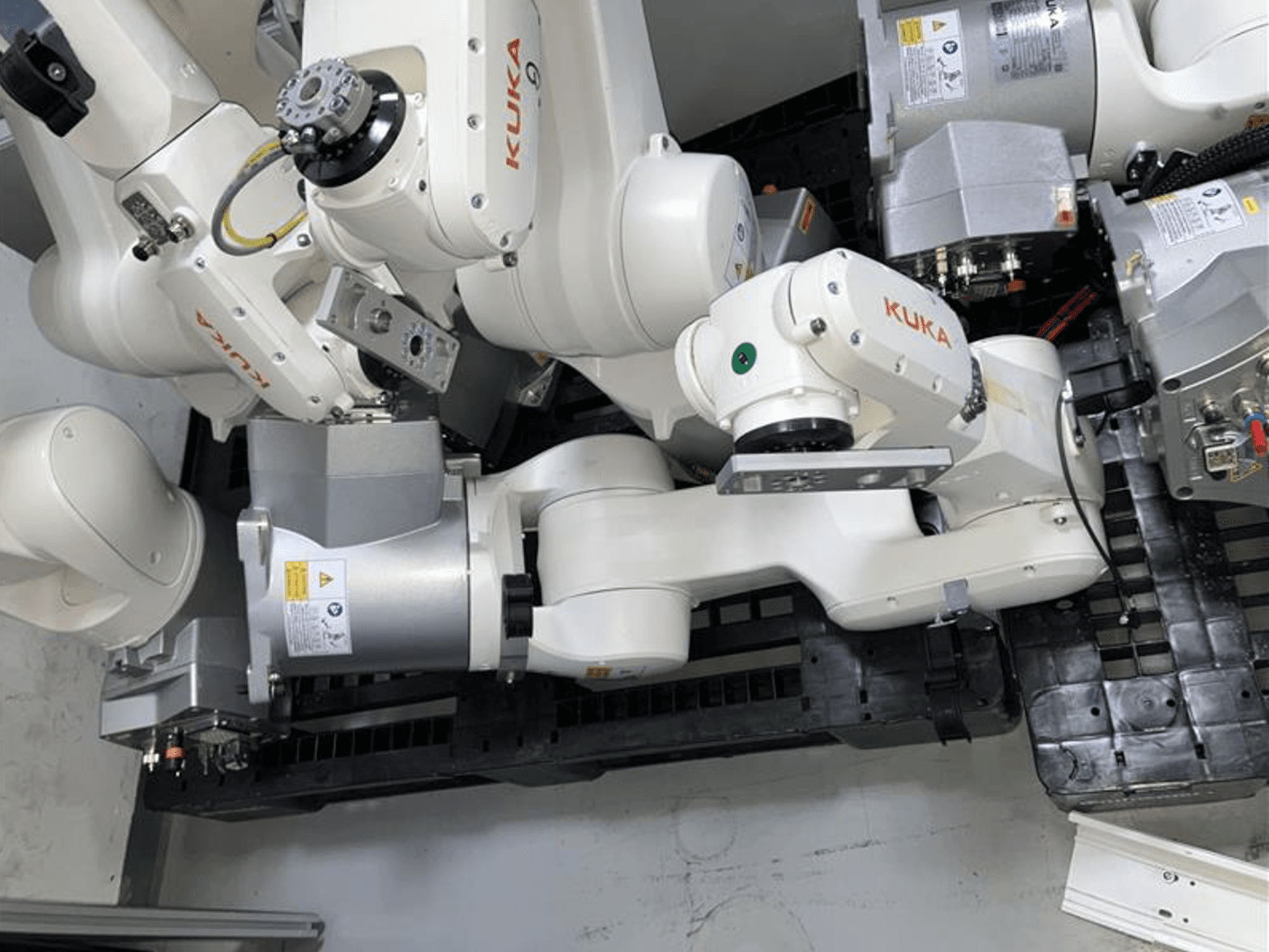 KUKA KR 6 R900 CR Roboterarm in der Draufsicht, mit mehreren Gelenken und Motoren, montiert auf einer schwarzen Basis mit Kabeln.