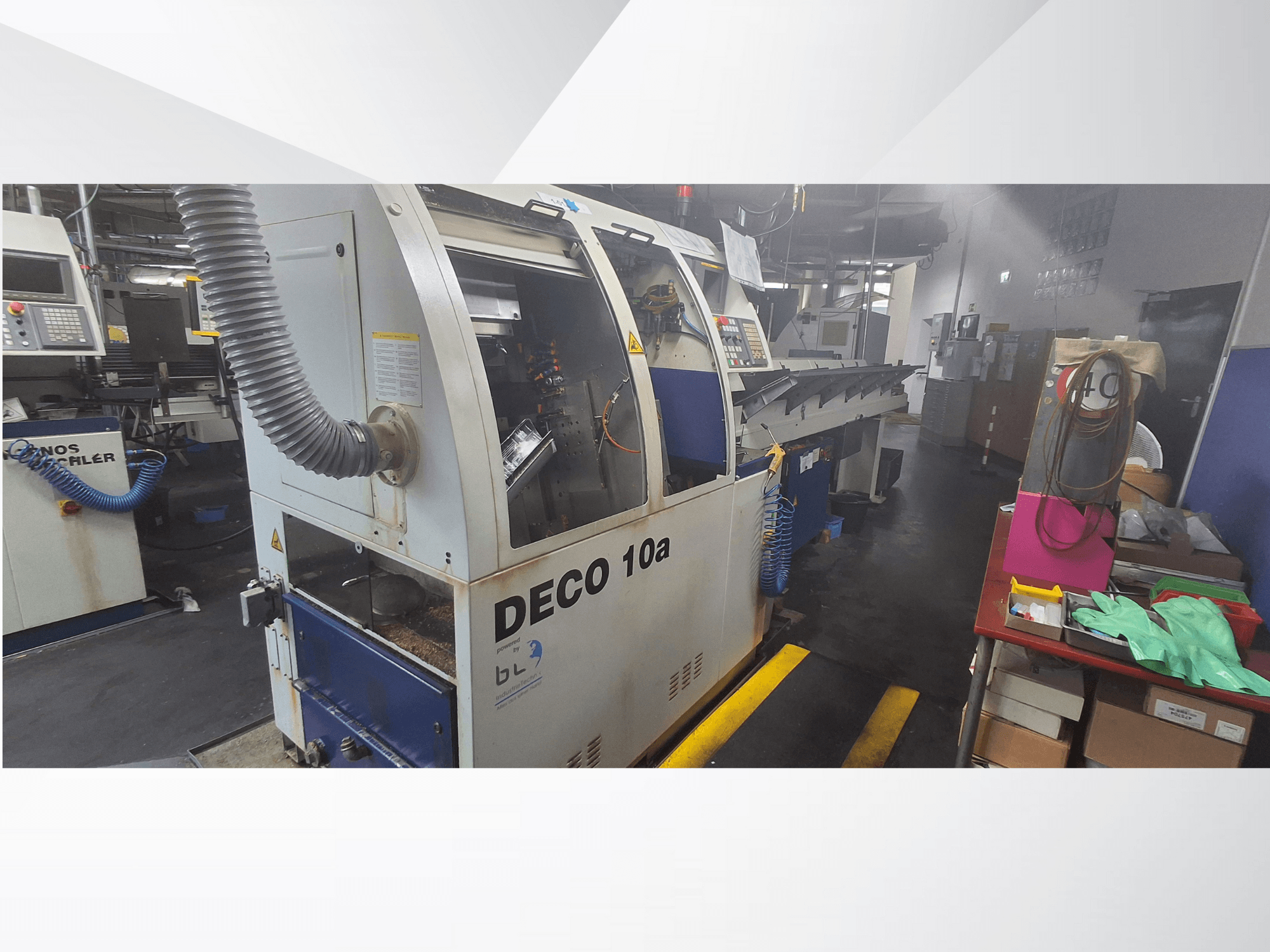 CNC-Maschine DECO 10a in einer Werkstatt, Vorderansicht; mit Bedienfeld und Staubabsaugung, daneben eine Werkbank.