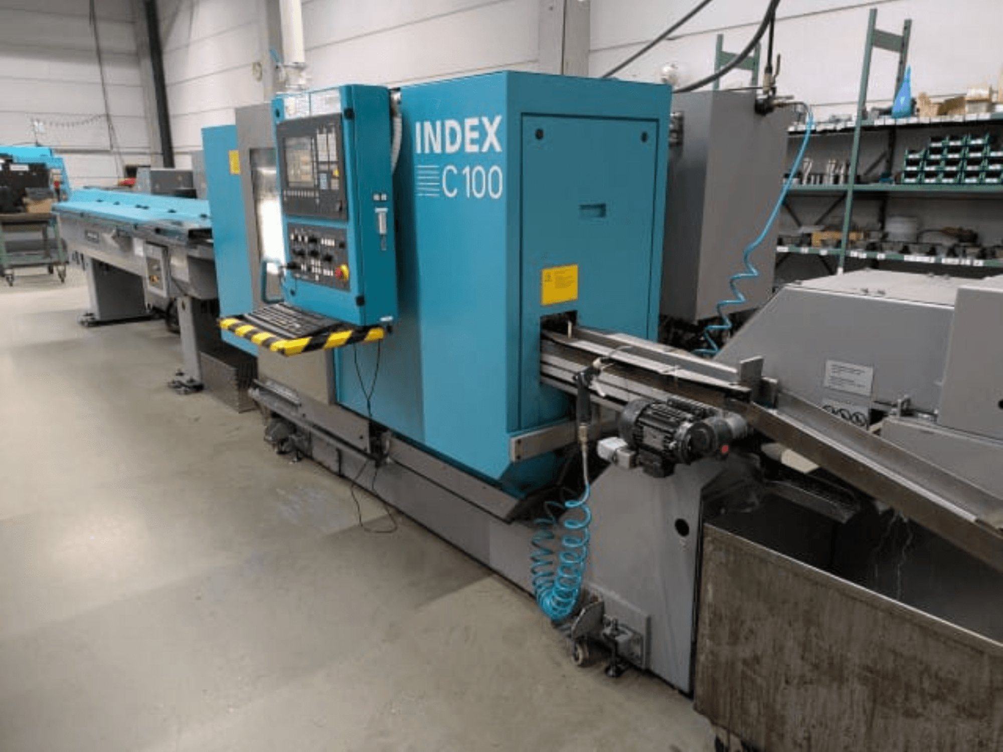 Index C100 Horizontal-Drehmaschine, Seitenansicht; ausgestattet mit einem Bedienfeld, einem Vorschubsystem und einem Spänesammelbehälter.