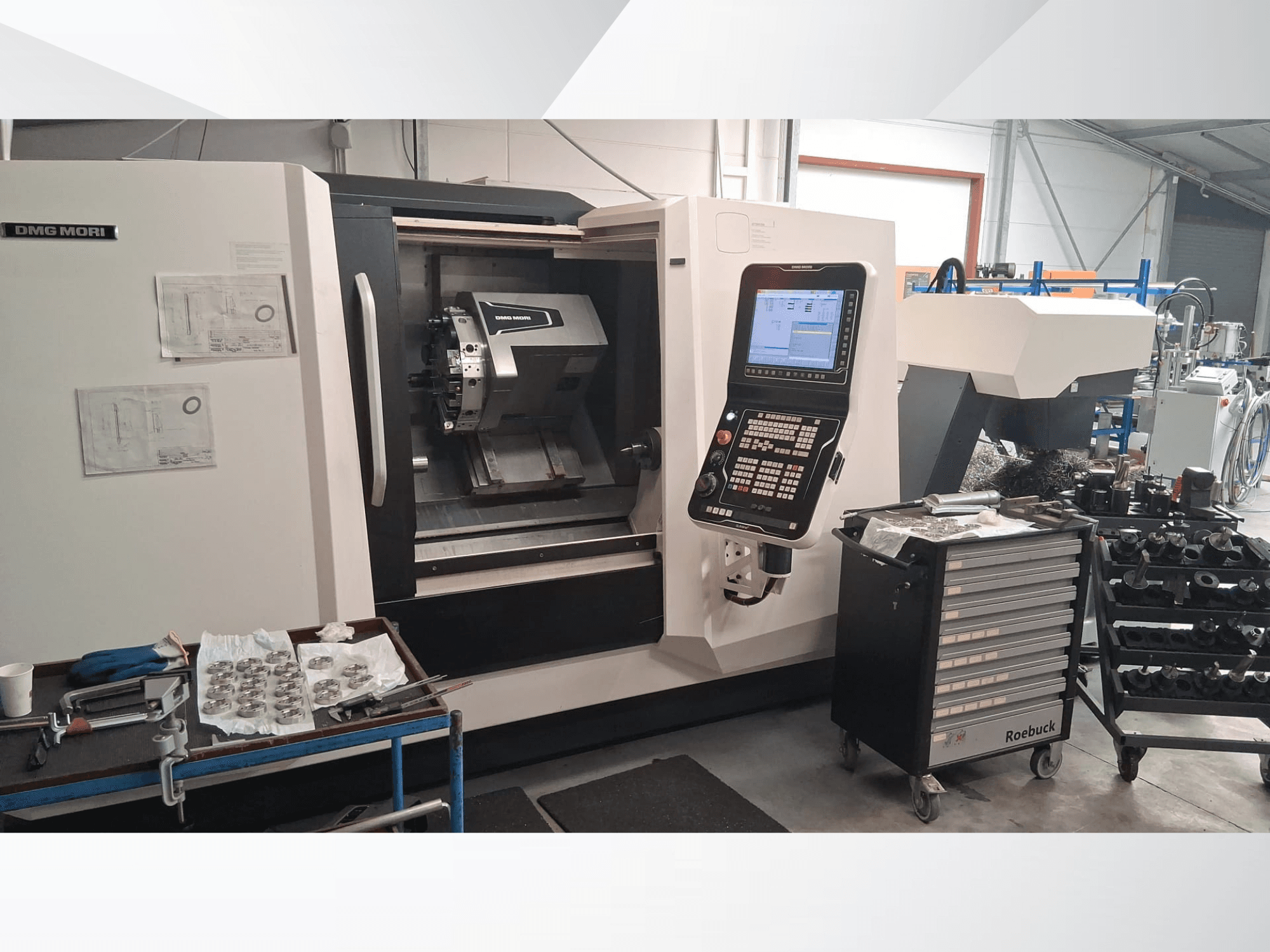 DMG MORI CLX450 Horizontal-Drehmaschine in der Vorderansicht mit Bedienfeld, Arbeitsbereich, Werkzeugen und Metallteilen.