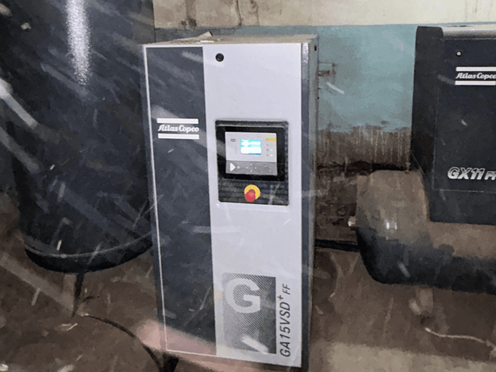 Atlas Copco GA15VSD+FF-Kompressor, Vorderansicht, einschließlich Bedienfeld mit Display und rotem Not-Aus-Schalter.