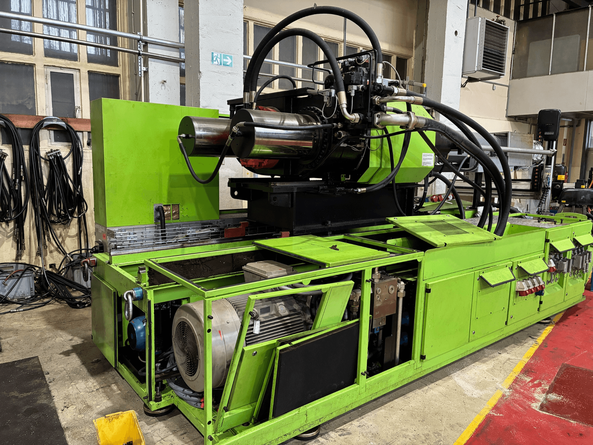 Grüne Industriemaschine mit Hydrauliksystem, Vorderansicht, mit Motor und verschiedenen Bedienfeldern.