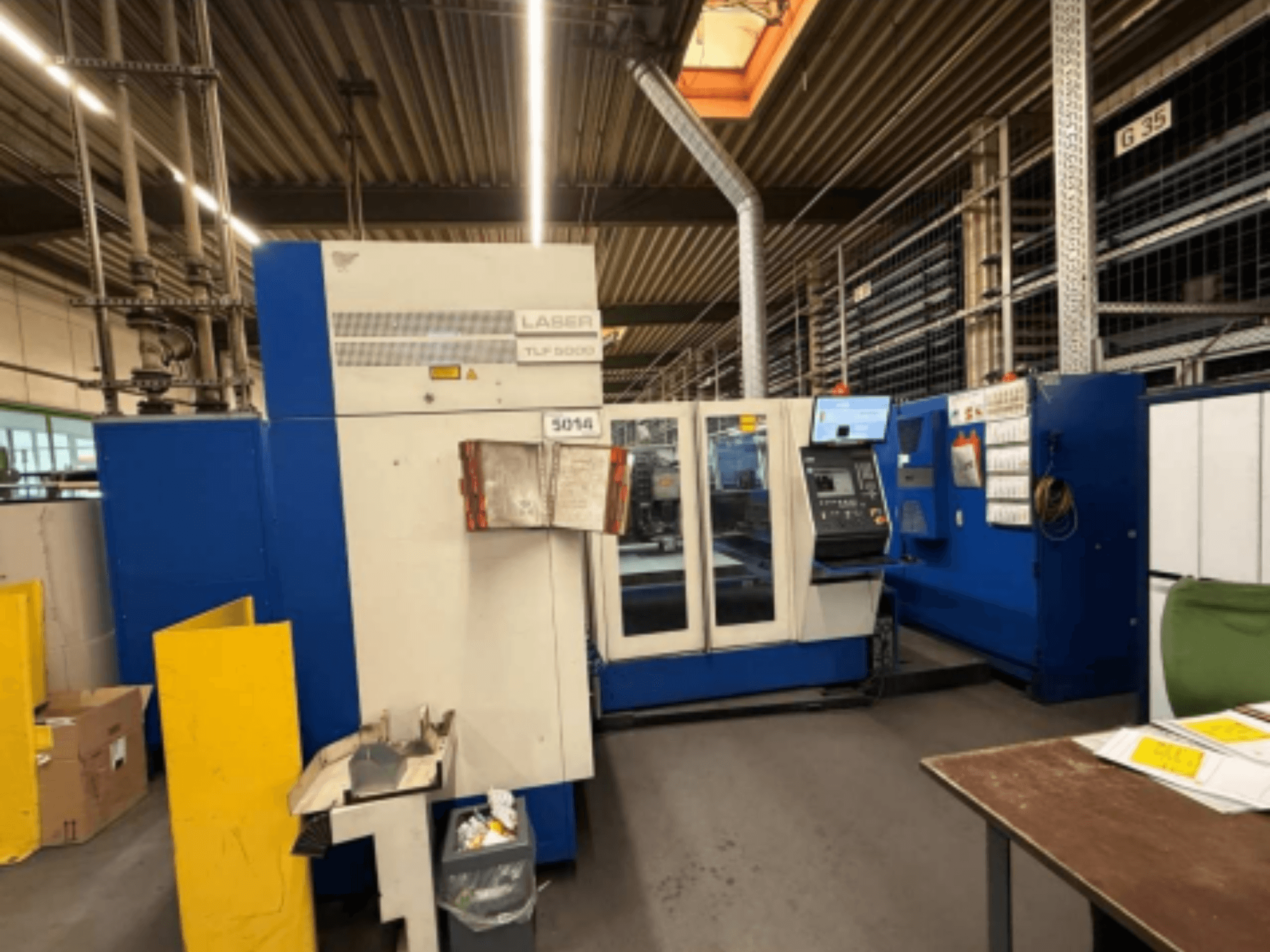 Frontansicht der TRUMPF Trumatic L 3050 CO2-Laserschneidmaschine, die das Bedienfeld und die Betriebsfunktionen in einer Werkstatt zeigt.