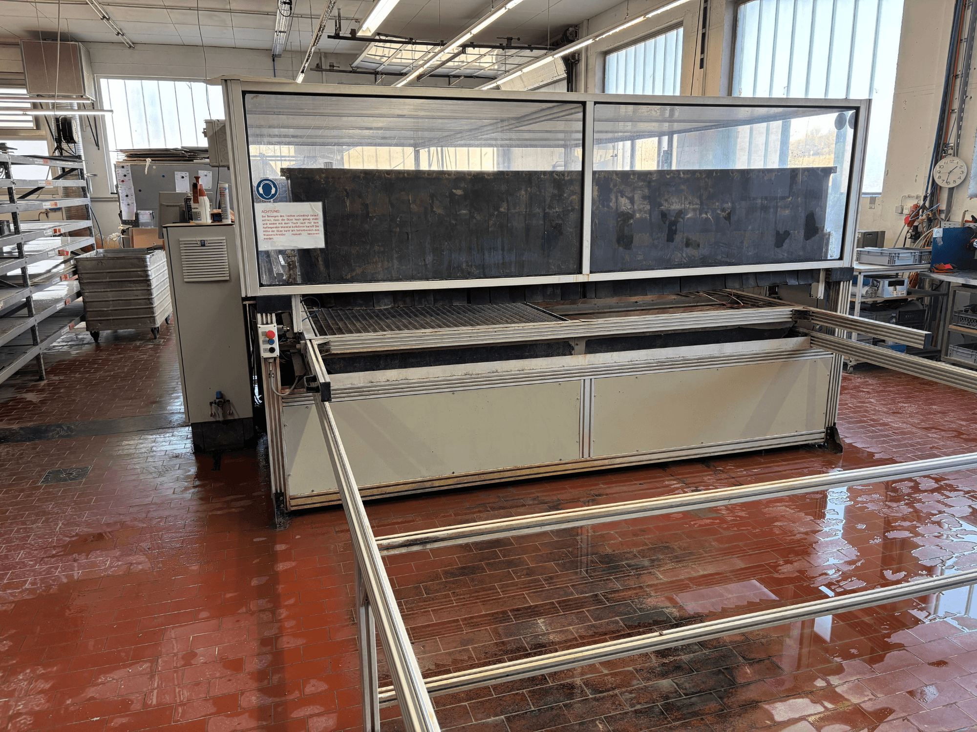 Wasserstrahlschneidemaschine „cutExpert variojet“ von EXPERT SYSTEMTECHNIK in einer Werkstatt, Vorderansicht, mit großer transparenter Abdeckung.