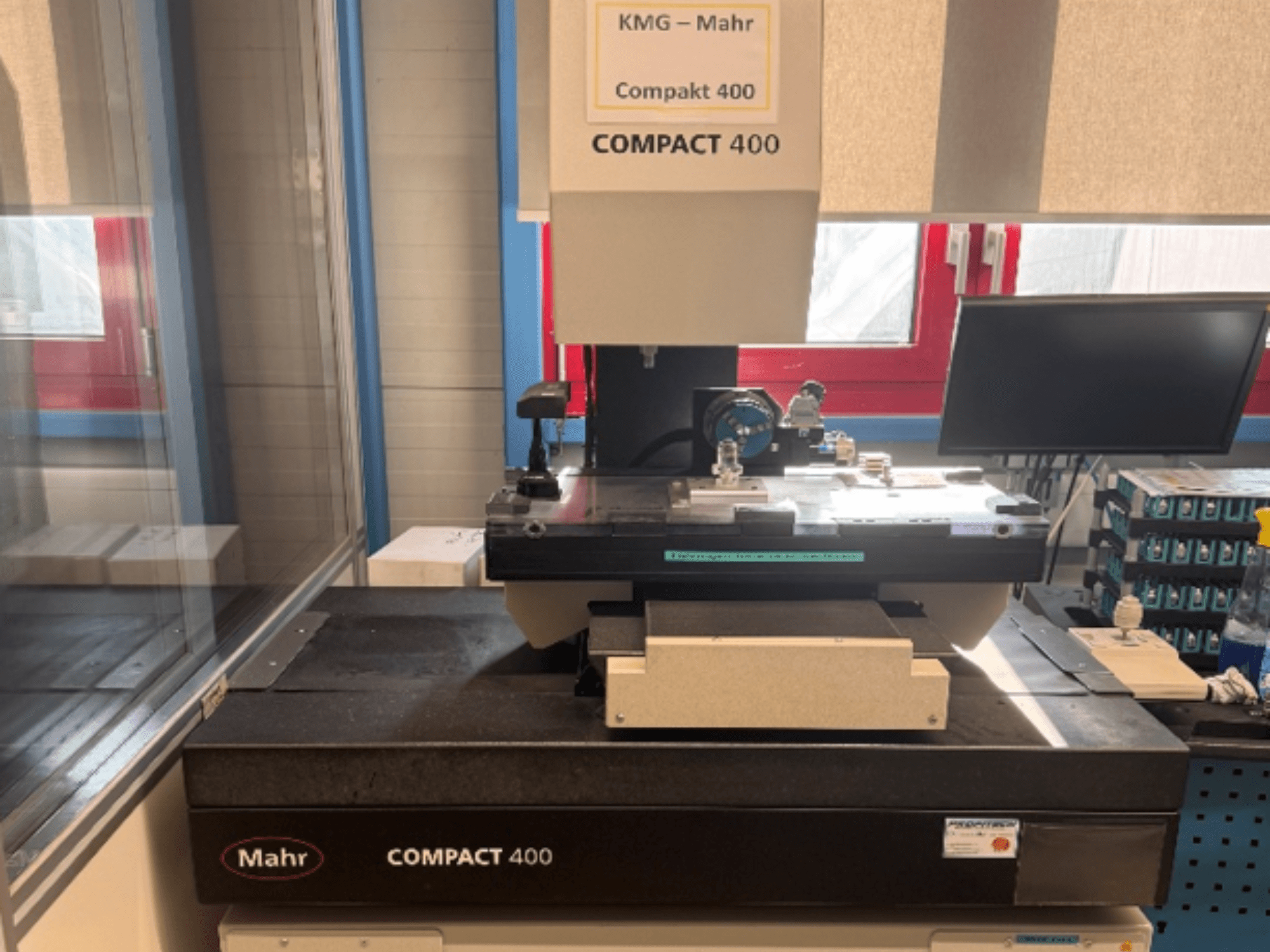 Die Koordinatenmessmaschine MAHR Compakt 400 in Frontansicht, mit Messkomponenten und einem daneben stehenden Monitor.