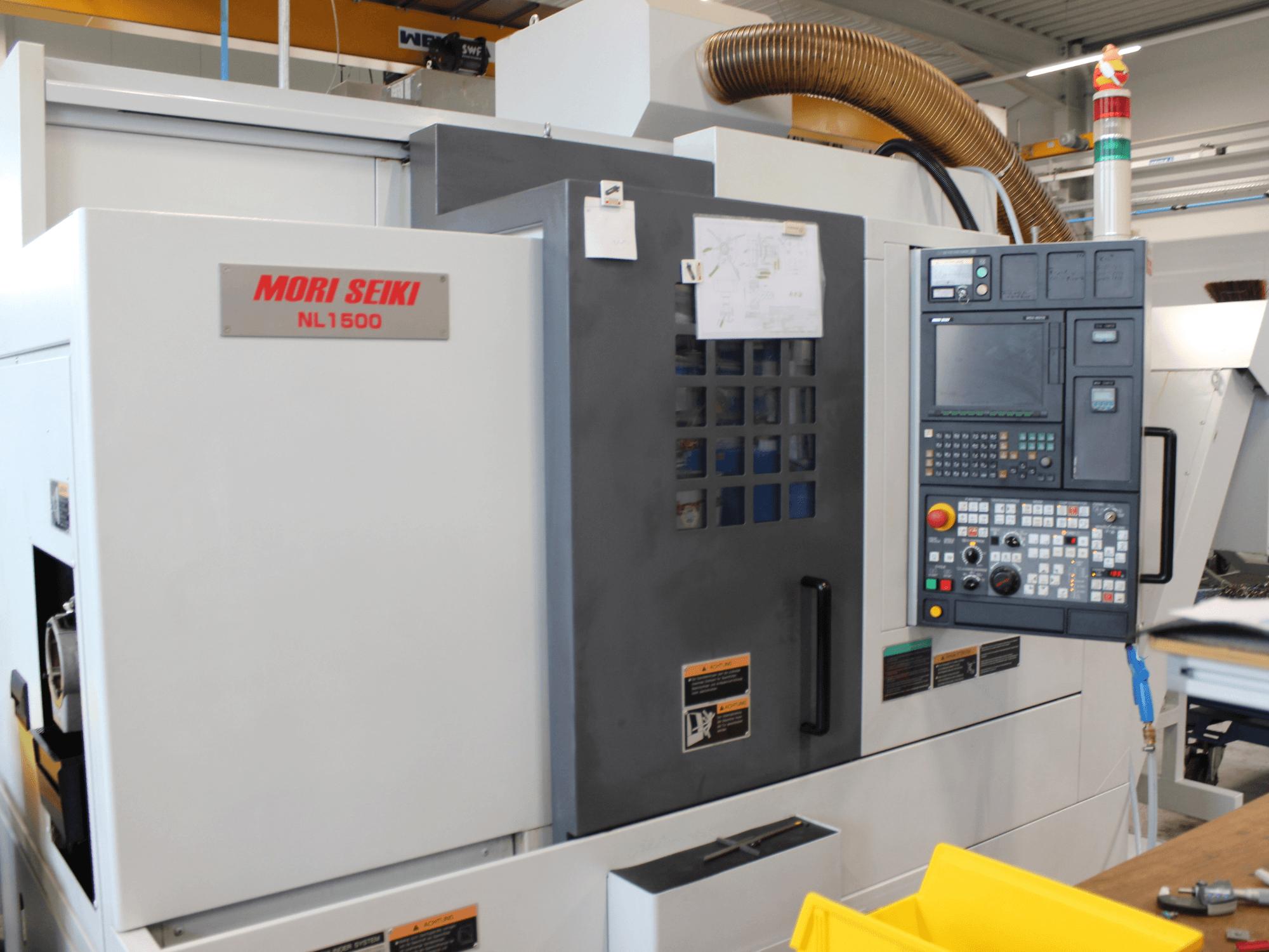 MORI SEIKI NL 1500 SY Dreh-Fräszentrum in Seitenansicht, mit Bedienfeld, Sicherheitshinweisen und Kühlsystem.