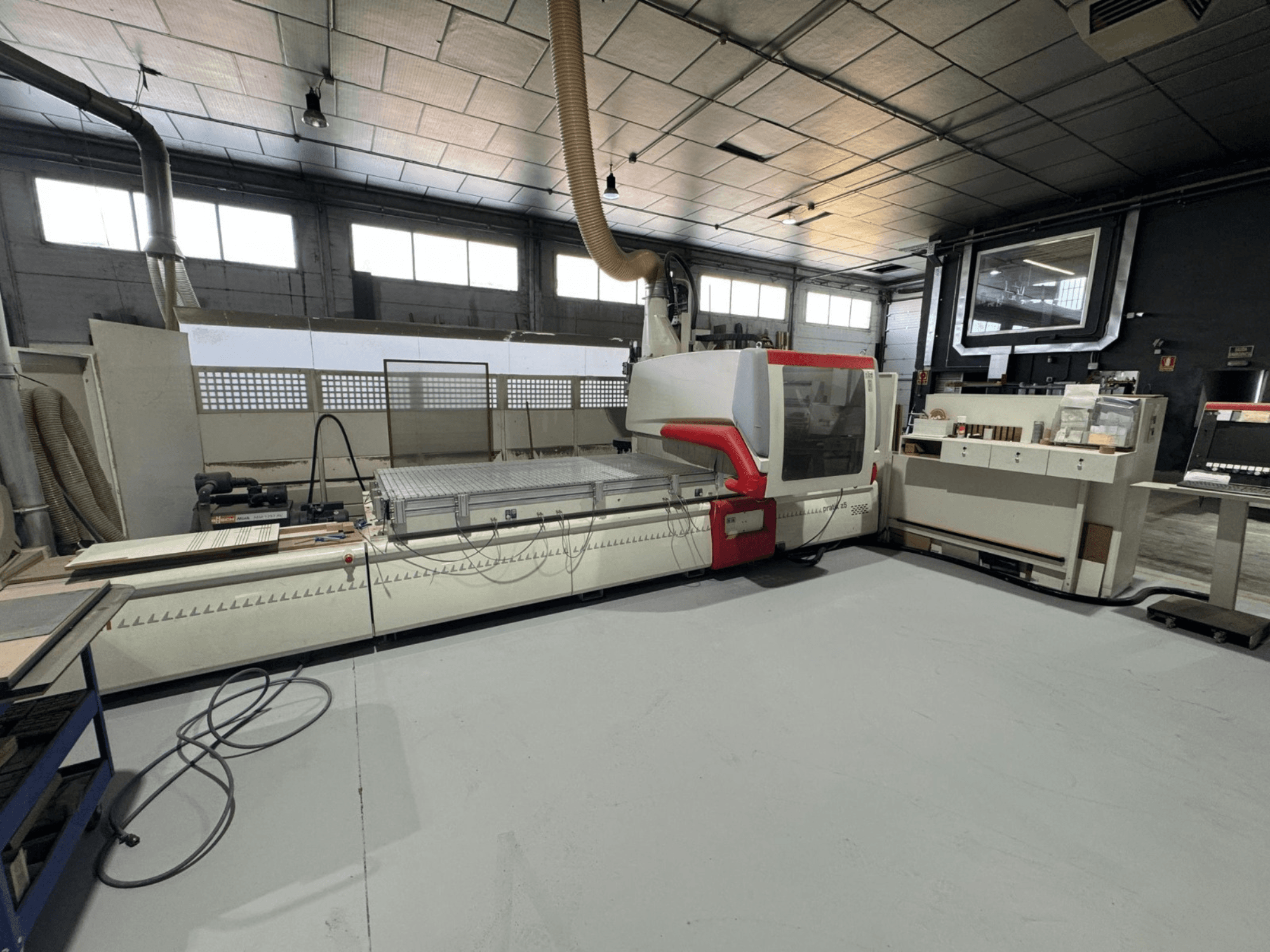 CNC-Maschine in einer Werkstatt, Vorderansicht mit roten Akzenten, ausgestattet mit Bedienfeld und Arbeitsfläche, für Präzisionsschnitte.