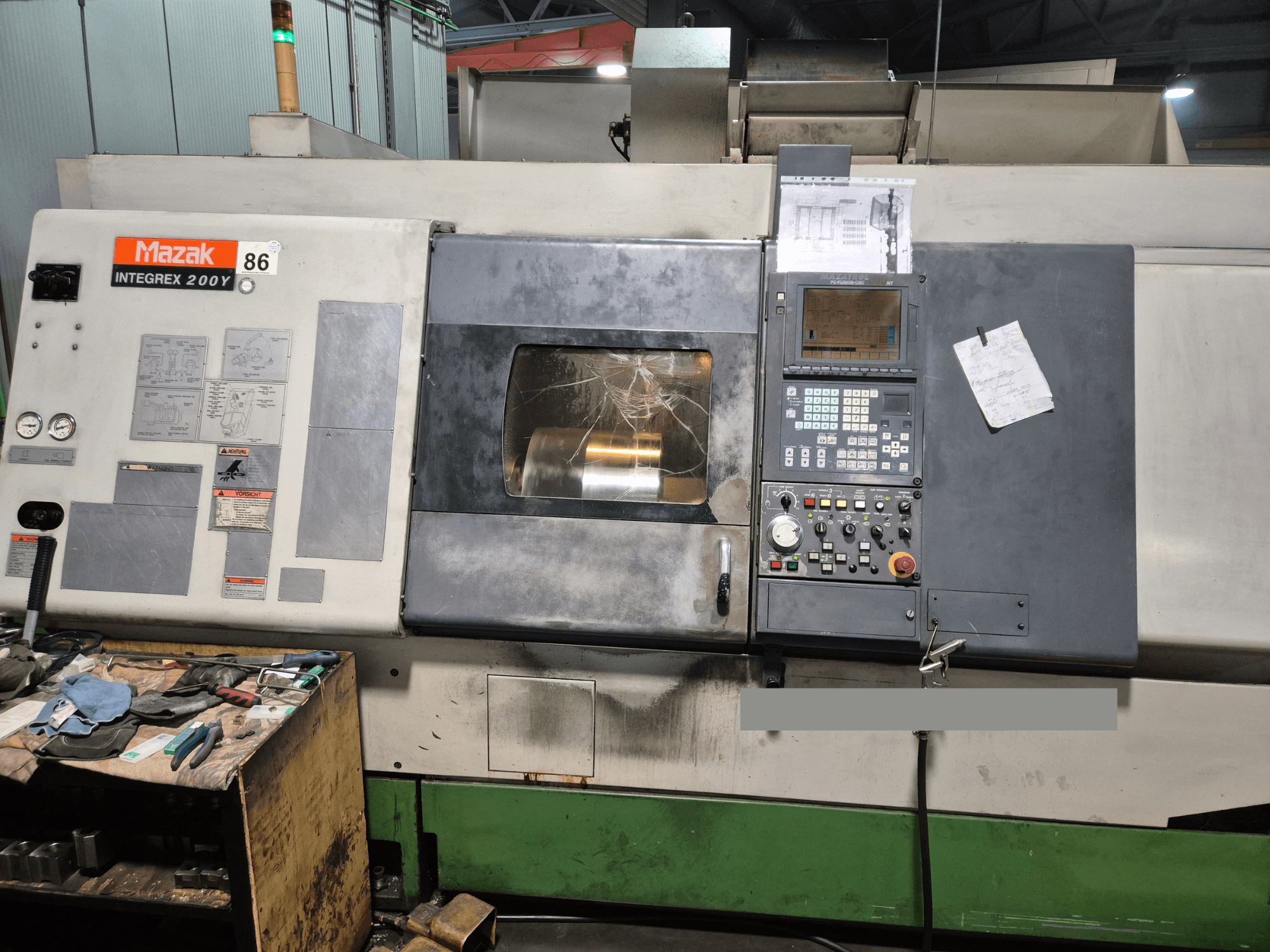 Mazak Integrex 200Y-Drehmaschine, Vorderansicht, mit Bedienfeld und Werkzeugen auf einer Werkbank. Sichtbare Messgeräte und Bildschirm.
