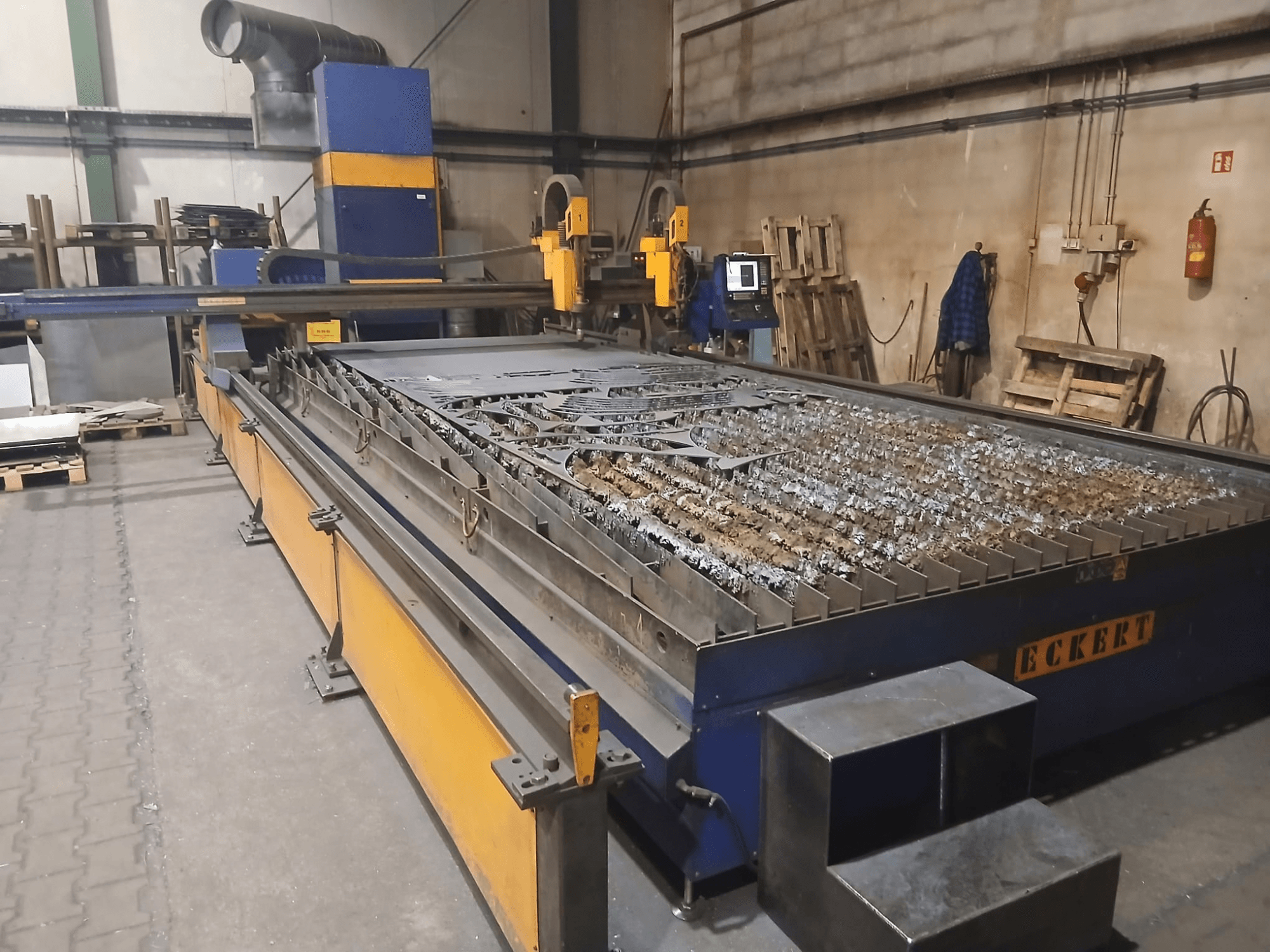 Plasmaschneidemaschine ECKERT JANTAR 2 in der Vorderansicht, mit großem Schneidetisch, auf dem Metallteile liegen, und Bedienelementen.