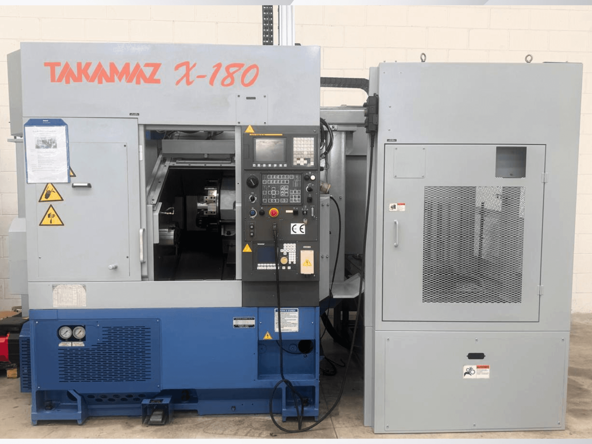 Horizontal-Drehmaschine Takamaz X-180, Vorderansicht mit Bedienfeld, Sicherheitshinweisen und angrenzendem Kühlaggregat.