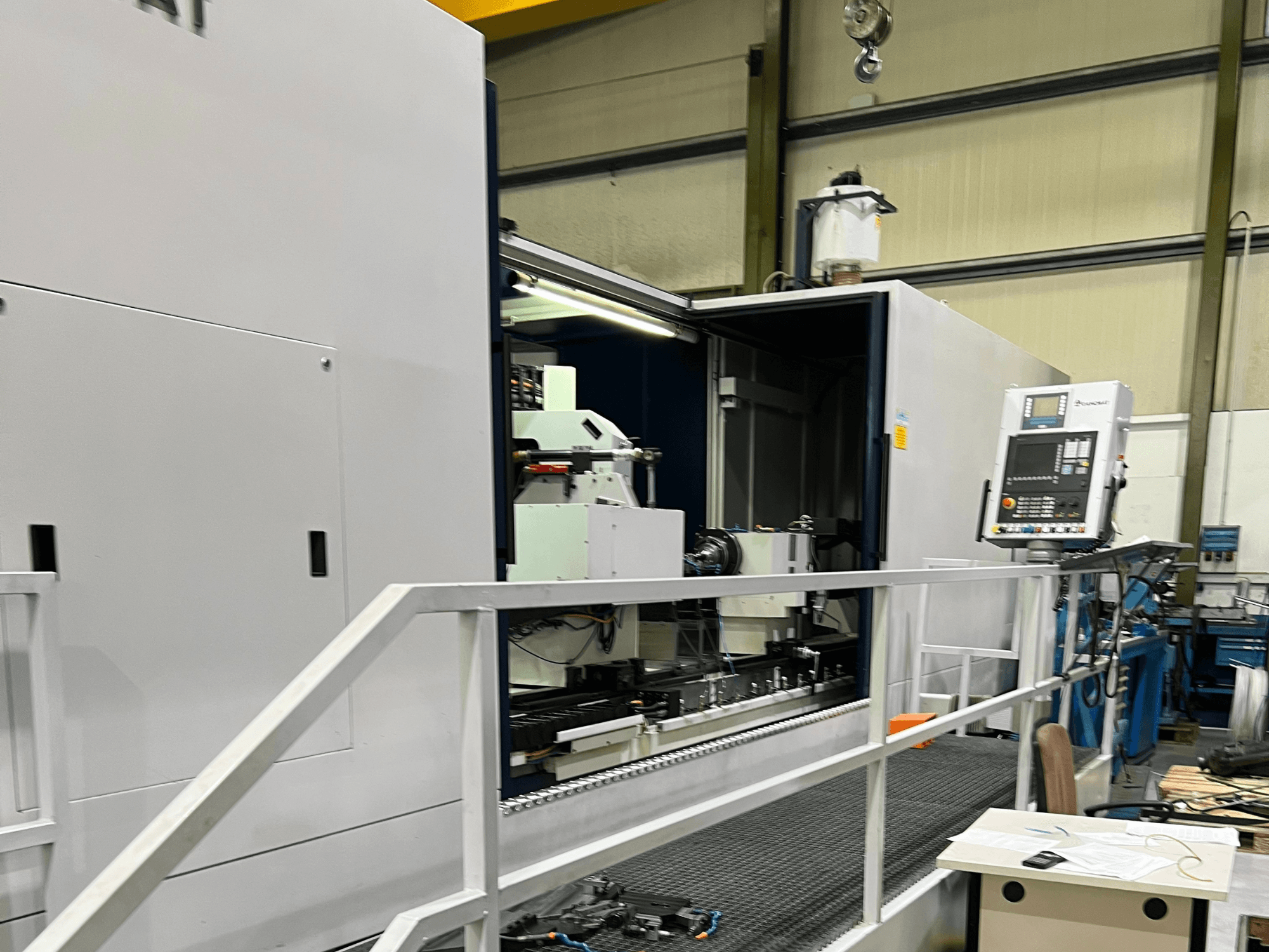 CNC-Bearbeitungszentrum mit offener Seitenansicht, die die Bedienelemente, den Werkzeughalter und die Hauptkomponente im Inneren zeigt. Markendetails nicht sichtbar.