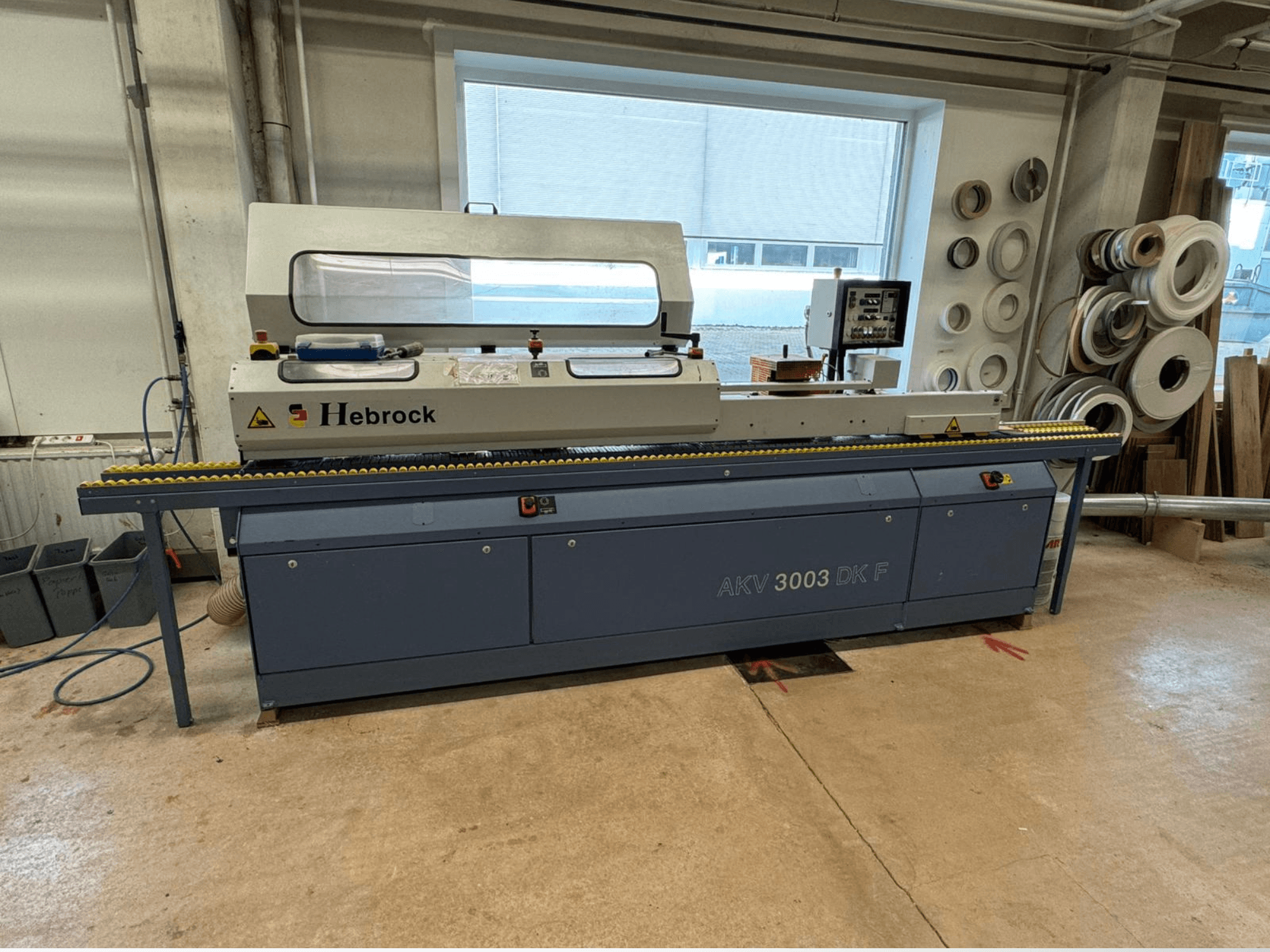 Hebrock AKV 3003 DK F Kantenanleimmaschine, Vorderansicht, mit Förderband und Bedienfeld, in einer Werkstatt.