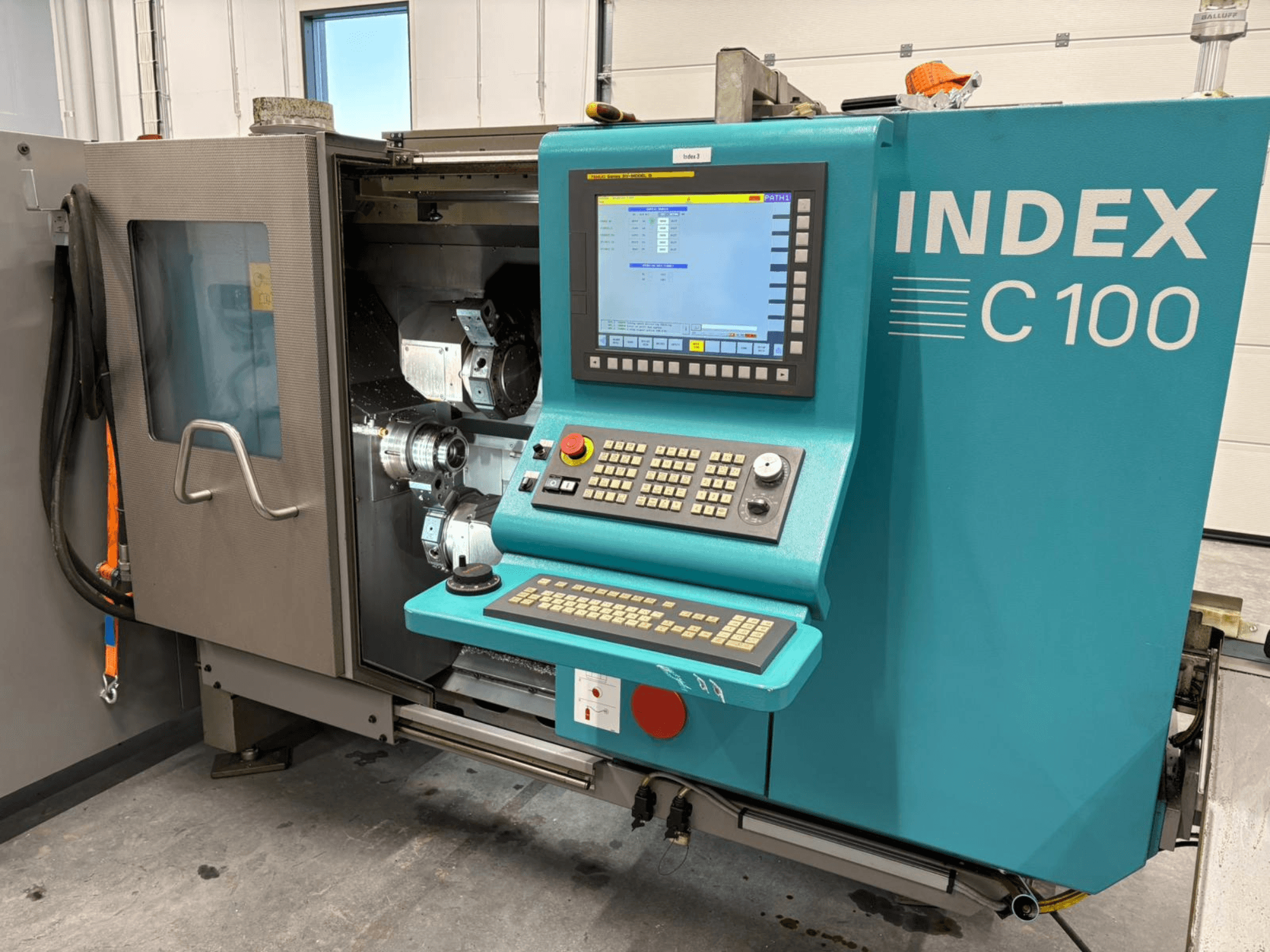 Vorderansicht der Index C100 Swiss Type Turning Machine mit Bedienfeld und offenem Gehäuse, das die internen Komponenten zeigt.