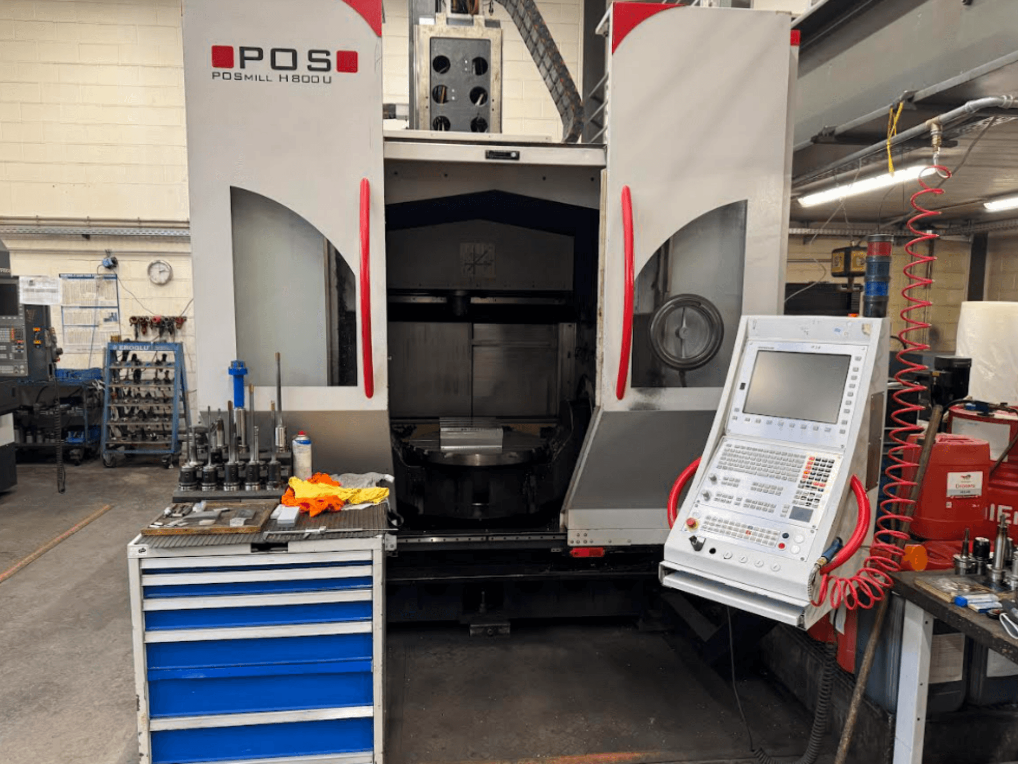 POSMILL H800 U CNC-Maschine von vorne gesehen, mit Blick auf das Bedienfeld und den Arbeitsbereich mit Werkzeugen und Geräten in der Nähe.